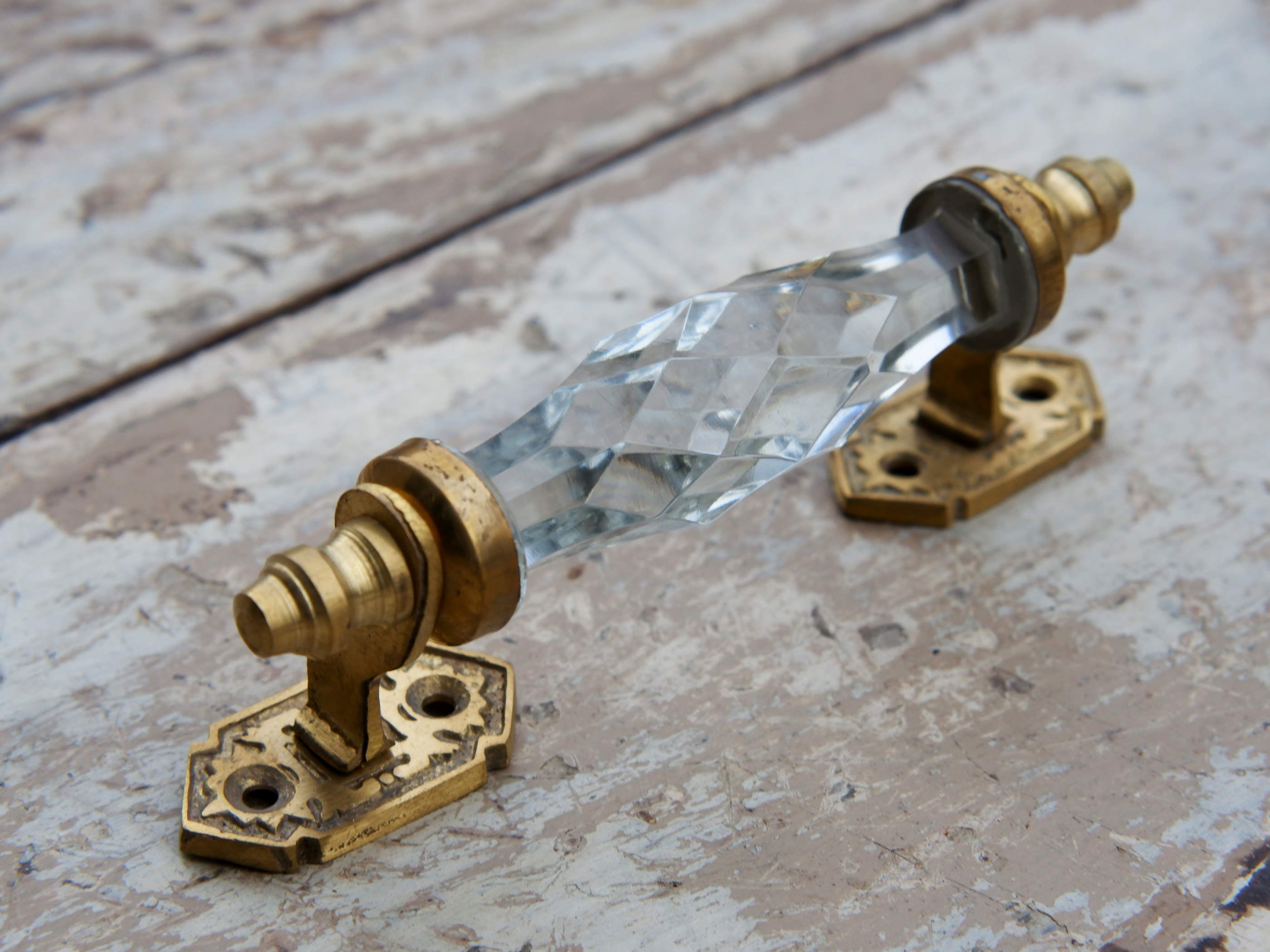 Maniglia in vetro lievemente sfaccettato di colore trasparente su supporto in metallo color oro. Disponibile in altri colori come da foto.  dimensioni 14x5x3cm