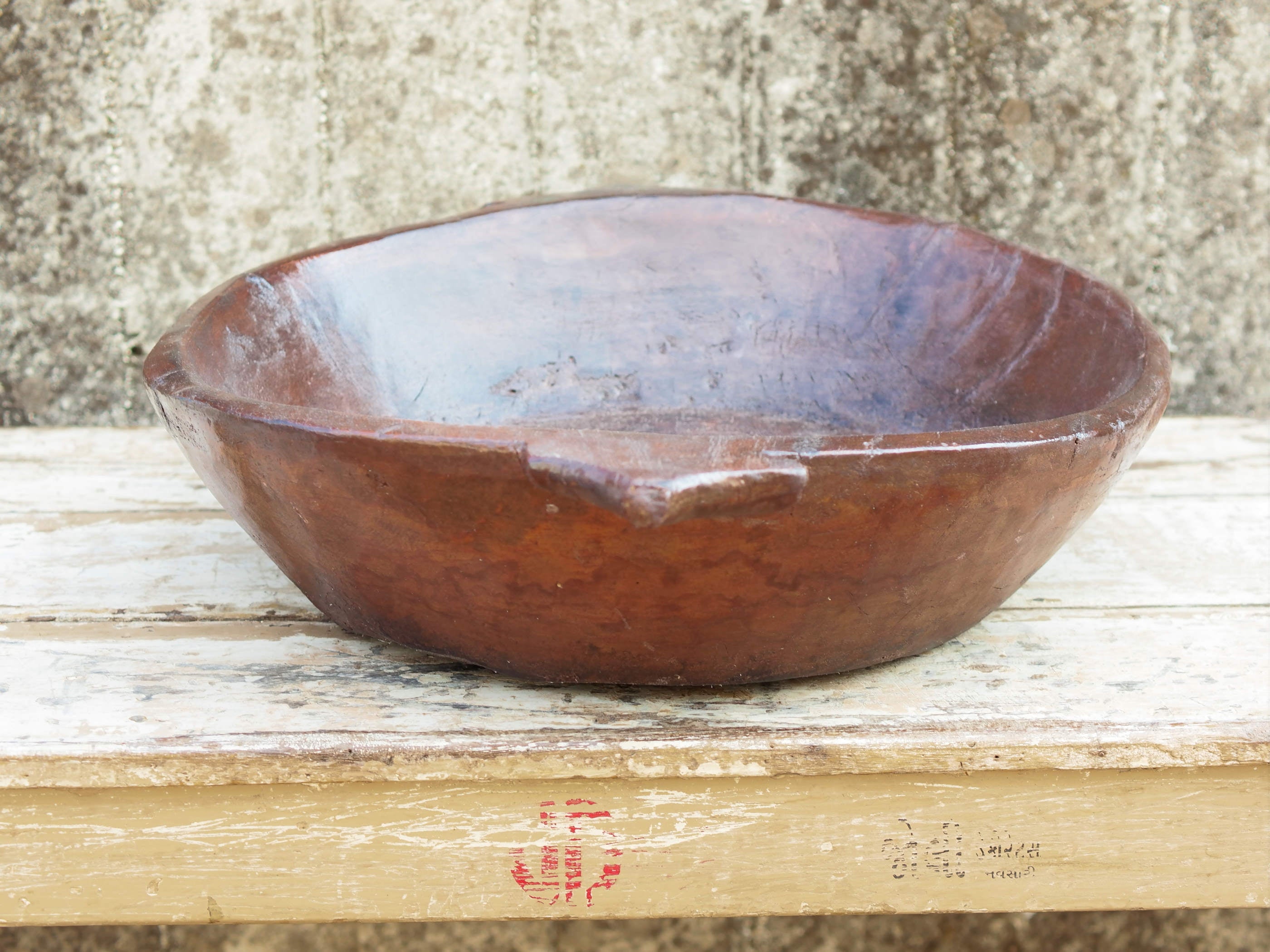 piatto in legno ricavato da un unico tronco di legno. usato in principio come piatto, setaccio per esiccare i cereali. tronco unico di teak massello databile inizio / metà 900.  dimensioni 61x49 h12cm.