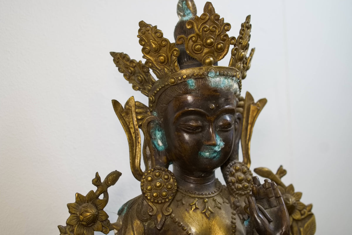 Primo piano del volto sereno e della corona rituale della divinità tibetana.