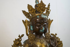 Primo piano del volto sereno e della corona rituale della divinità tibetana.