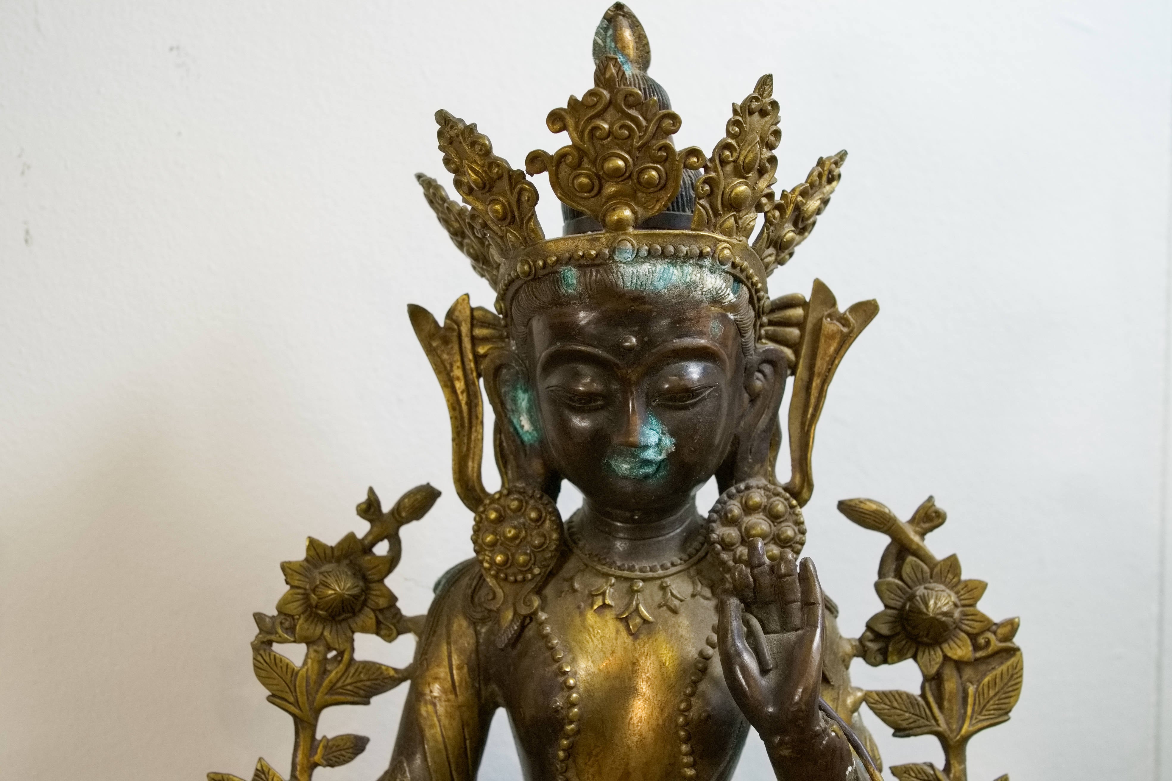 Primo piano del volto sereno e della corona rituale della divinità tibetana.
