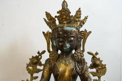 Primo piano del volto sereno e della corona rituale della divinità tibetana.