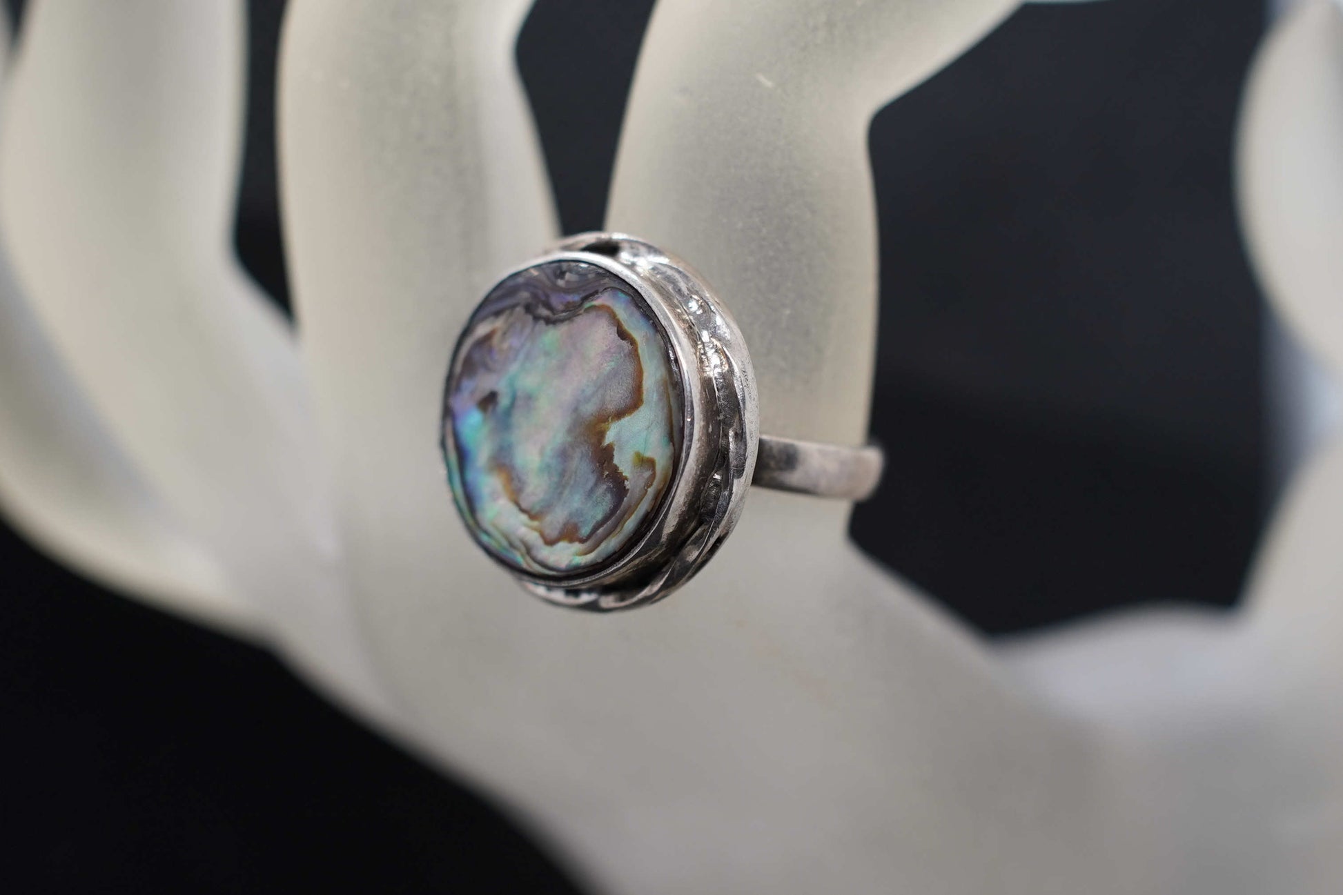 Dettaglio dei riflessi iridescenti della madreperla sul medaglione scudo dell'anello