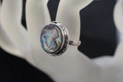 Dettaglio dei riflessi iridescenti della madreperla sul medaglione scudo dell'anello