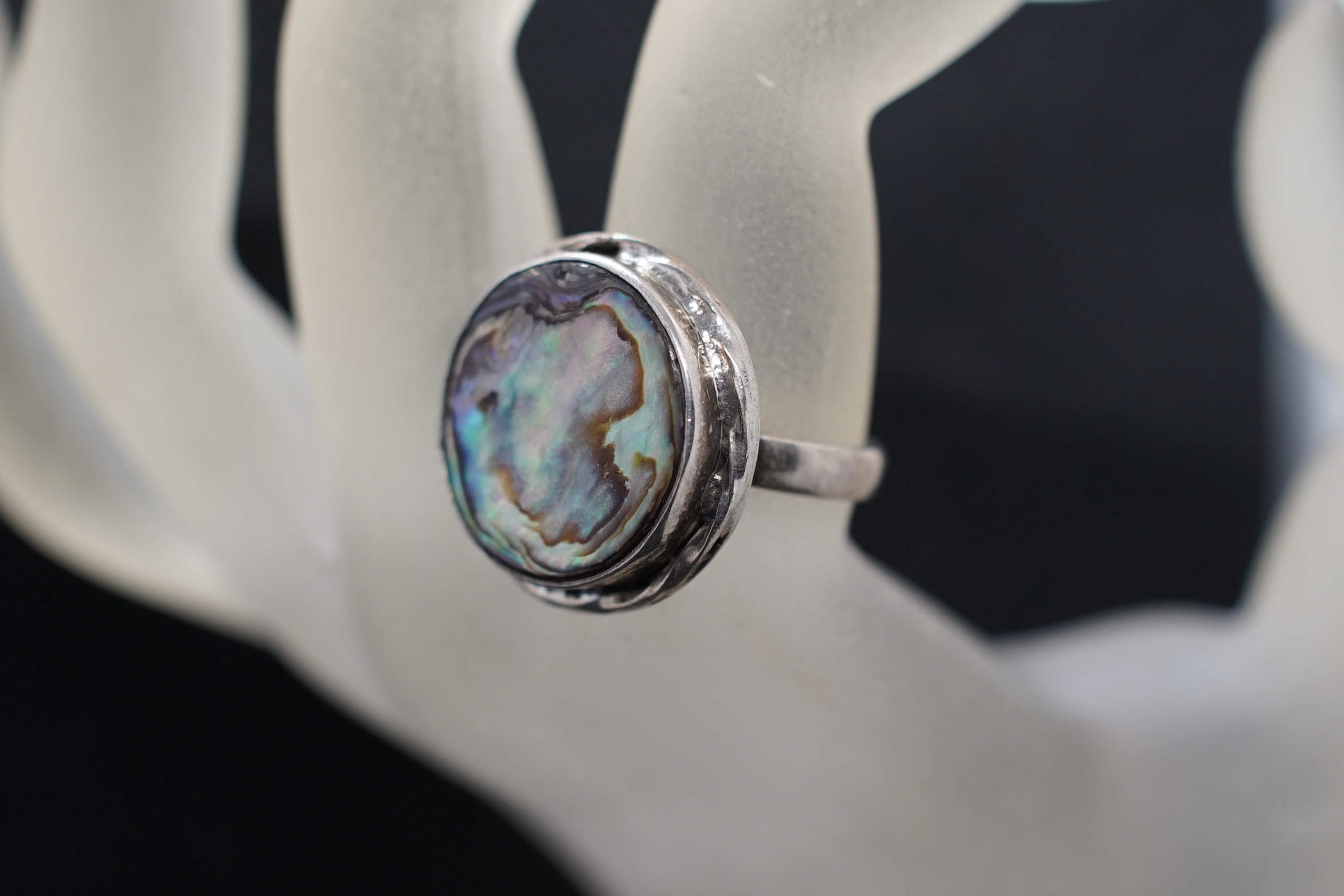 Dettaglio dei riflessi iridescenti della madreperla sul medaglione scudo dell'anello