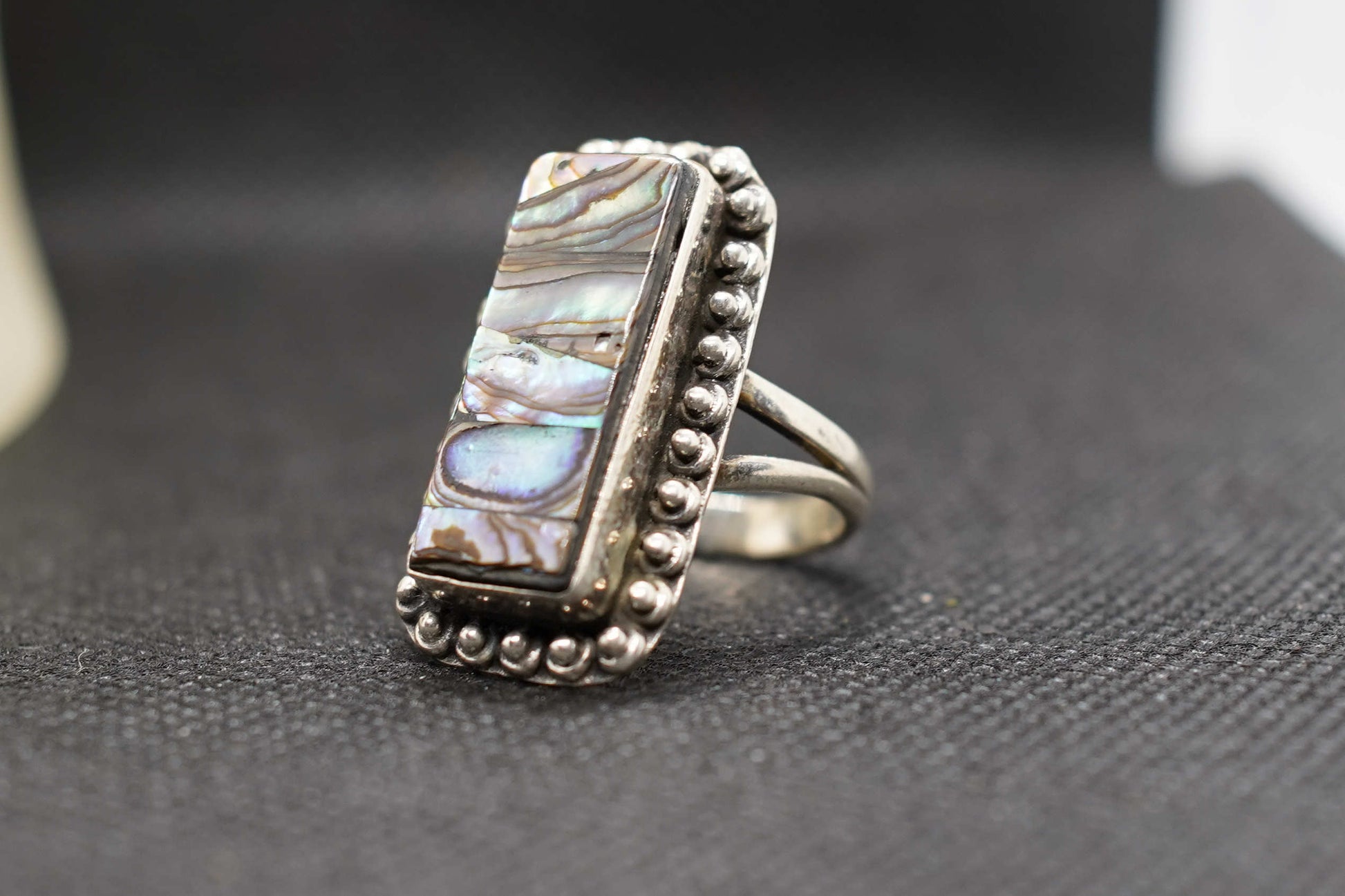 Dettaglio dei riflessi iridescenti della madreperla sul medaglione scudo dell'anello