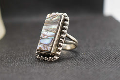 Dettaglio dei riflessi iridescenti della madreperla sul medaglione scudo dell'anello
