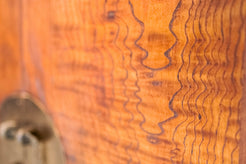 Primo piano della venatura fiammata dell'olmo portata a legno naturale grazie al restauro conservativo con gommalacca.