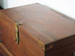 Baule Indiano in legno di teak con rinforzi laterali in ottone. Venivano usate in genere dagli Inglesi per i comuni spostamenti per contenere spezie, trucco e gioielli di uso giornaliero. Pezzo interamente originale e di difficile reperibilità. Databile primi '900.  Dimensioni 82x47 h46cm