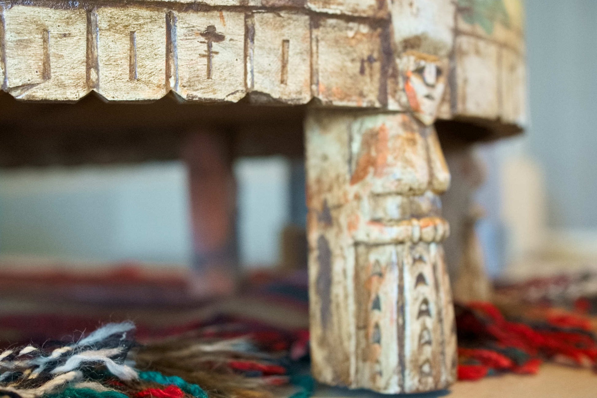 Dettaglio ravvicinato dei piedi intagliati artigianalmente con figurine umane.