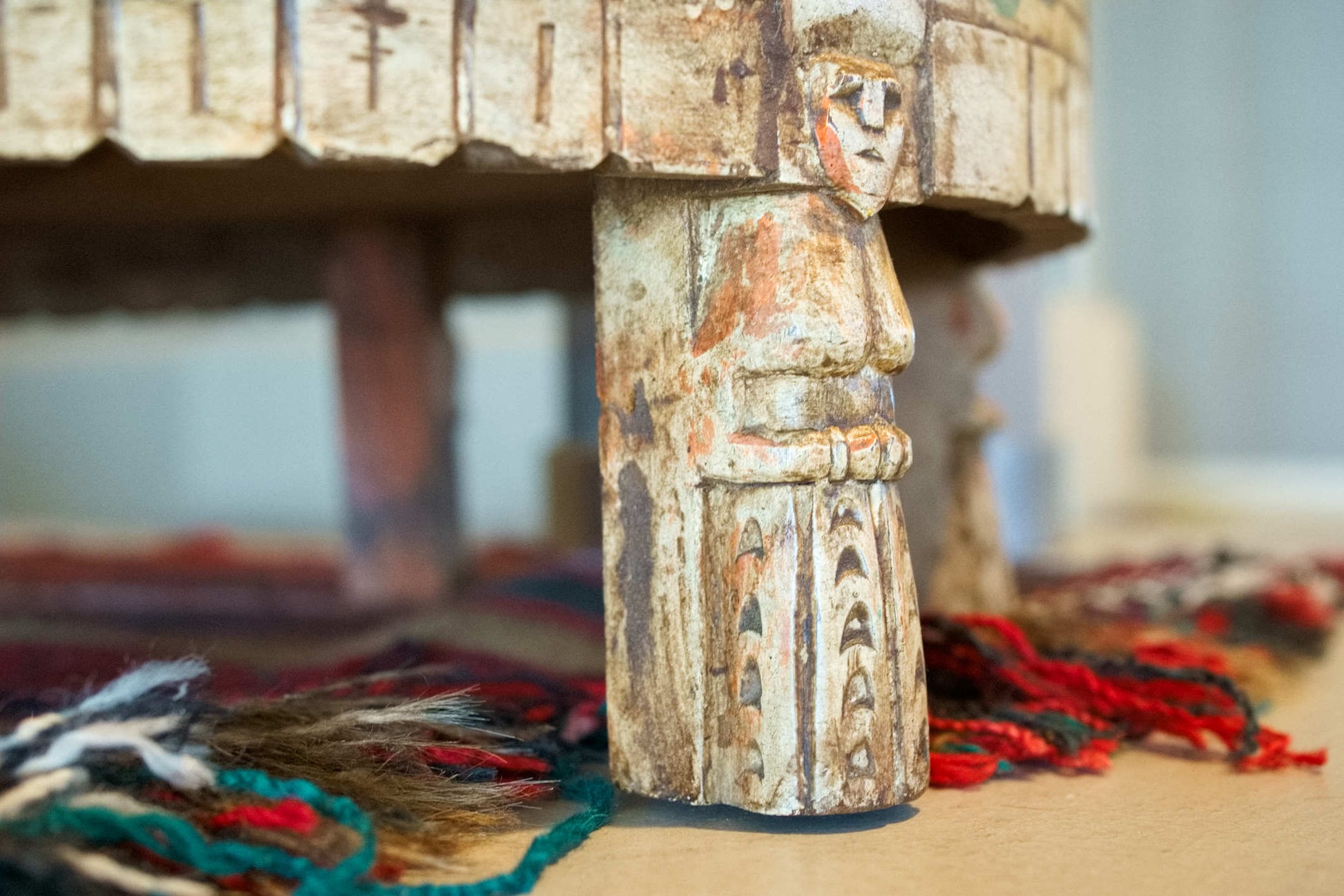 Dettaglio ravvicinato dei piedi intagliati artigianalmente con figurine umane.