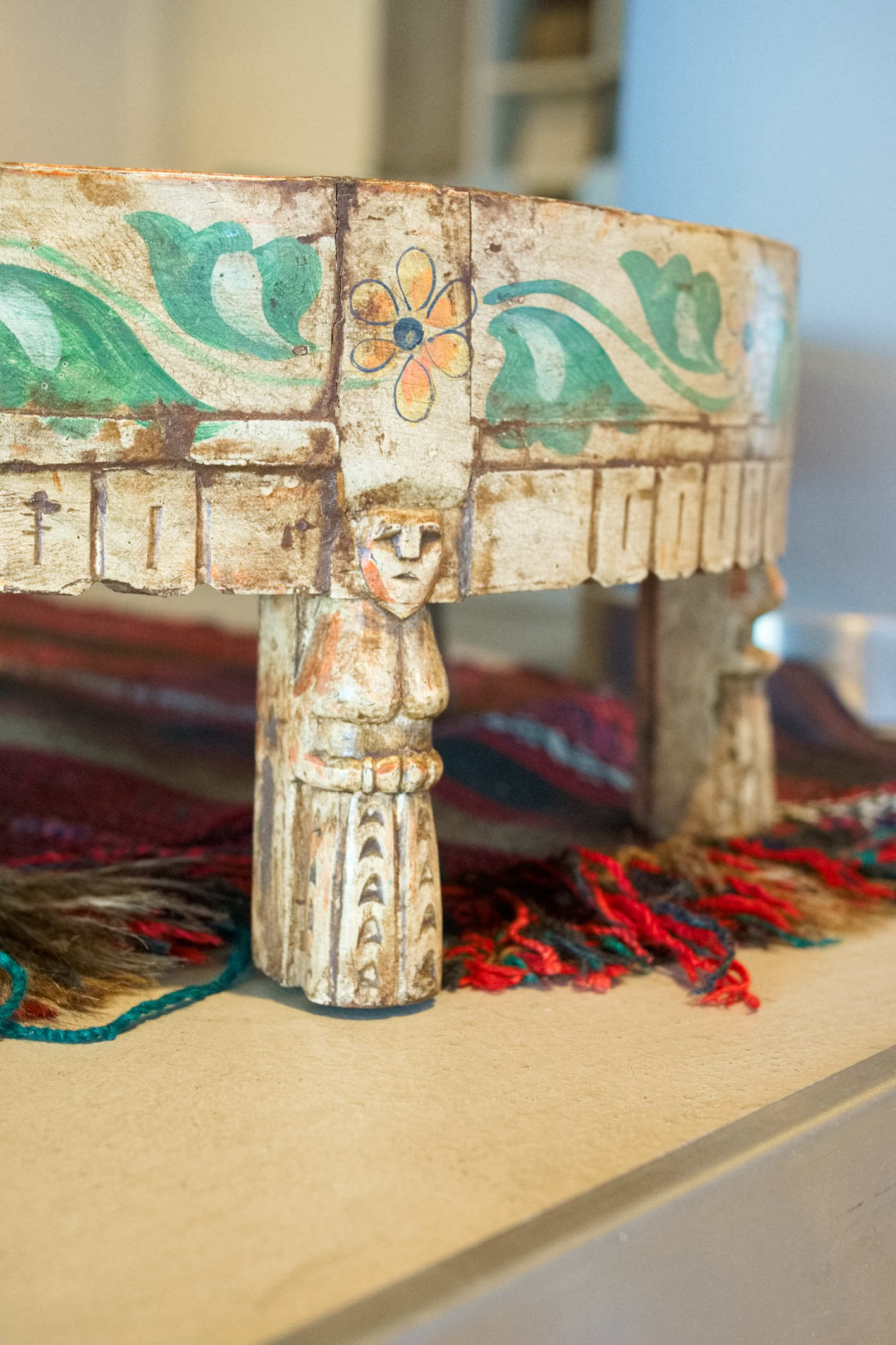 Dettaglio ravvicinato dei piedi intagliati artigianalmente con figurine umane.