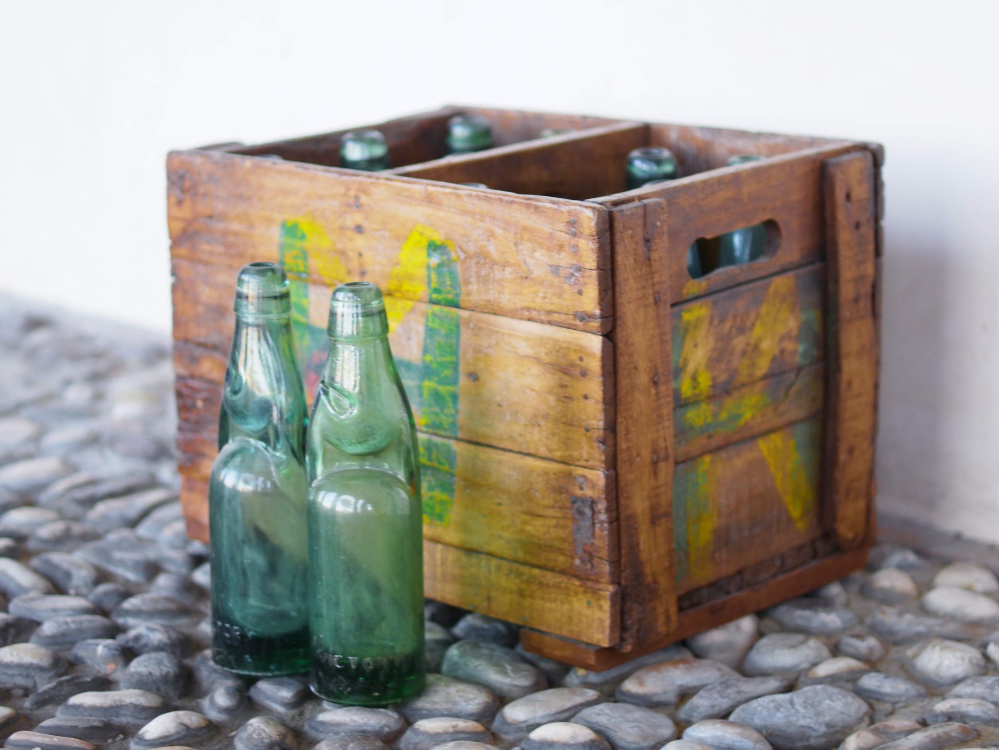 Cassa in legno con 12 bottiglie per acqua frizzante. In uso in India dagli anni 40 ai primi anni 90 le bottiglie venovano usate per fare l'acqua frizzante. Bottiglie e cassetta interamente lavorate in modo artigianale, pezzo vintage originale e di difficile reperibilità se completo come l'articolo in foto. Ogni bottiglia è differente l'una dall'altra ed ogni cassa ha delle caratteristiche relative a fornitore, regione...  dimensioni 30x30xh40cm