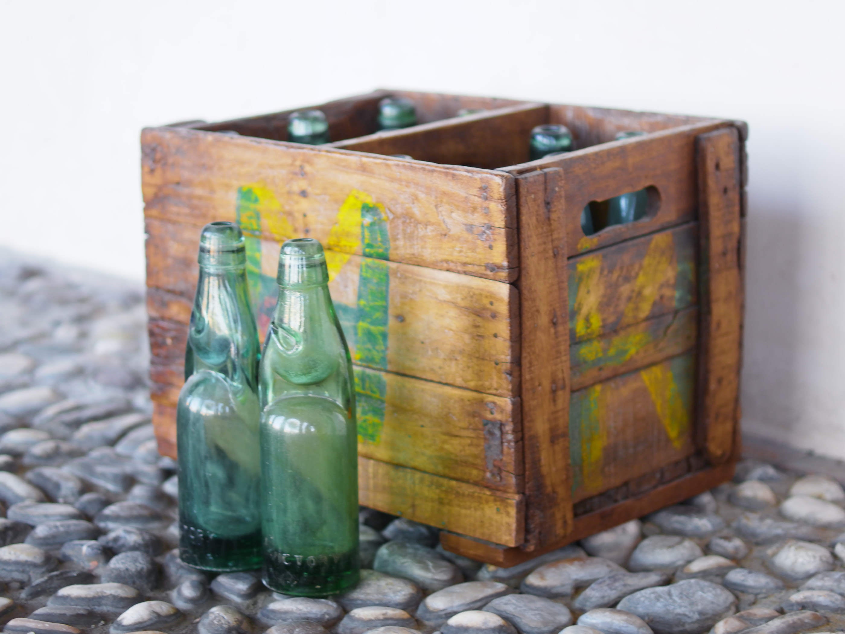 Cassa in legno con 12 bottiglie per acqua frizzante. In uso in India dagli anni 40 ai primi anni 90 le bottiglie venovano usate per fare l'acqua frizzante. Bottiglie e cassetta interamente lavorate in modo artigianale, pezzo vintage originale e di difficile reperibilità se completo come l'articolo in foto. Ogni bottiglia è differente l'una dall'altra ed ogni cassa ha delle caratteristiche relative a fornitore, regione...  dimensioni 30x30xh40cm