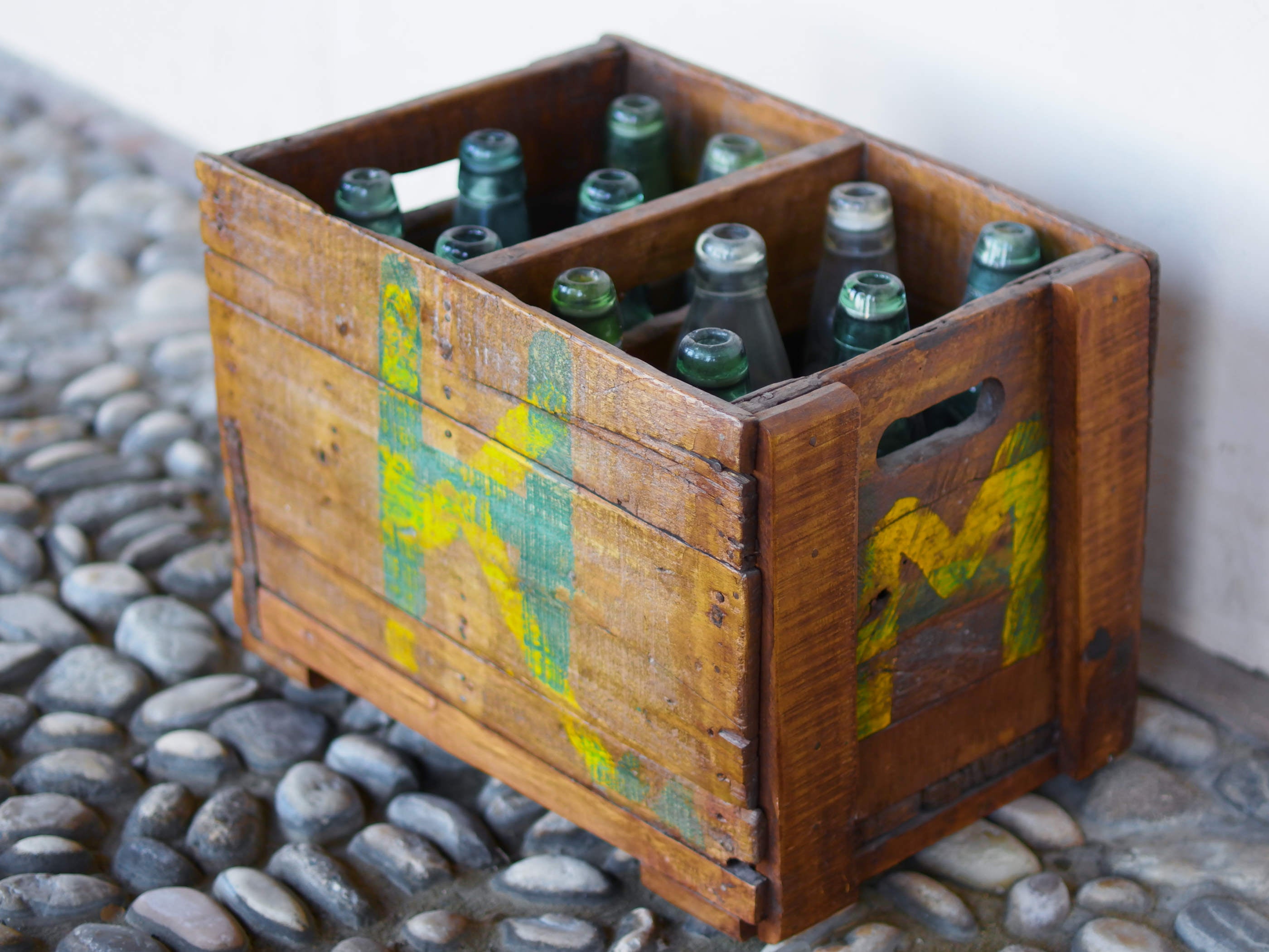 Cassa in legno con 12 bottiglie per acqua frizzante. In uso in India dagli anni 40 ai primi anni 90 le bottiglie venovano usate per fare l'acqua frizzante. Bottiglie e cassetta interamente lavorate in modo artigianale, pezzo vintage originale e di difficile reperibilità se completo come l'articolo in foto. Ogni bottiglia è differente l'una dall'altra ed ogni cassa ha delle caratteristiche relative a fornitore, regione...  dimensioni 30x30xh40cm