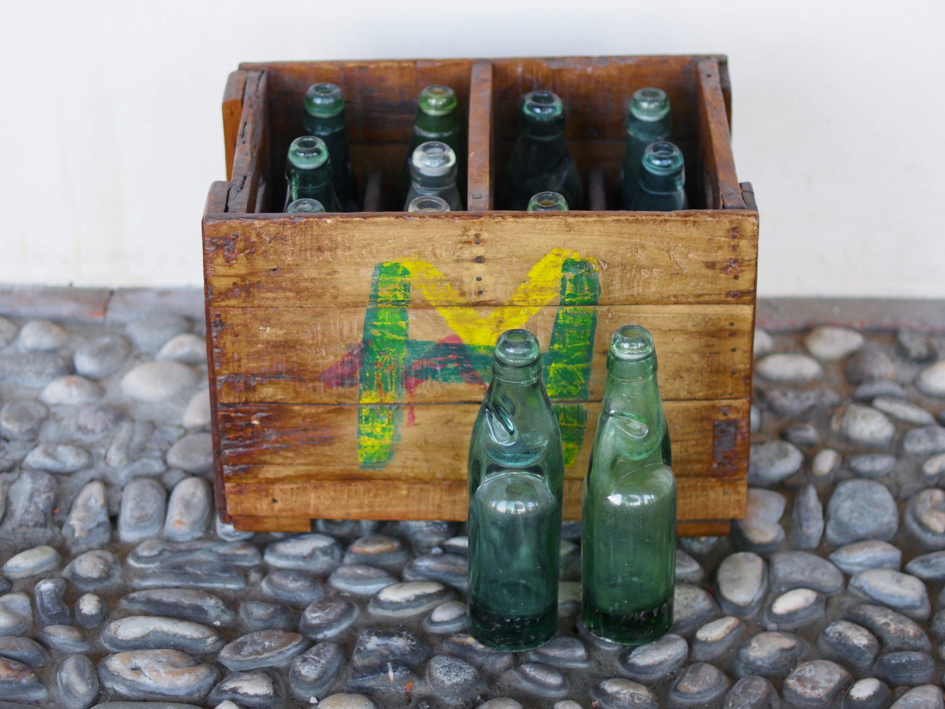 Cassa in legno con 12 bottiglie per acqua frizzante. In uso in India dagli anni 40 ai primi anni 90 le bottiglie venovano usate per fare l'acqua frizzante. Bottiglie e cassetta interamente lavorate in modo artigianale, pezzo vintage originale e di difficile reperibilità se completo come l'articolo in foto. Ogni bottiglia è differente l'una dall'altra ed ogni cassa ha delle caratteristiche relative a fornitore, regione...  dimensioni 30x30xh40cm