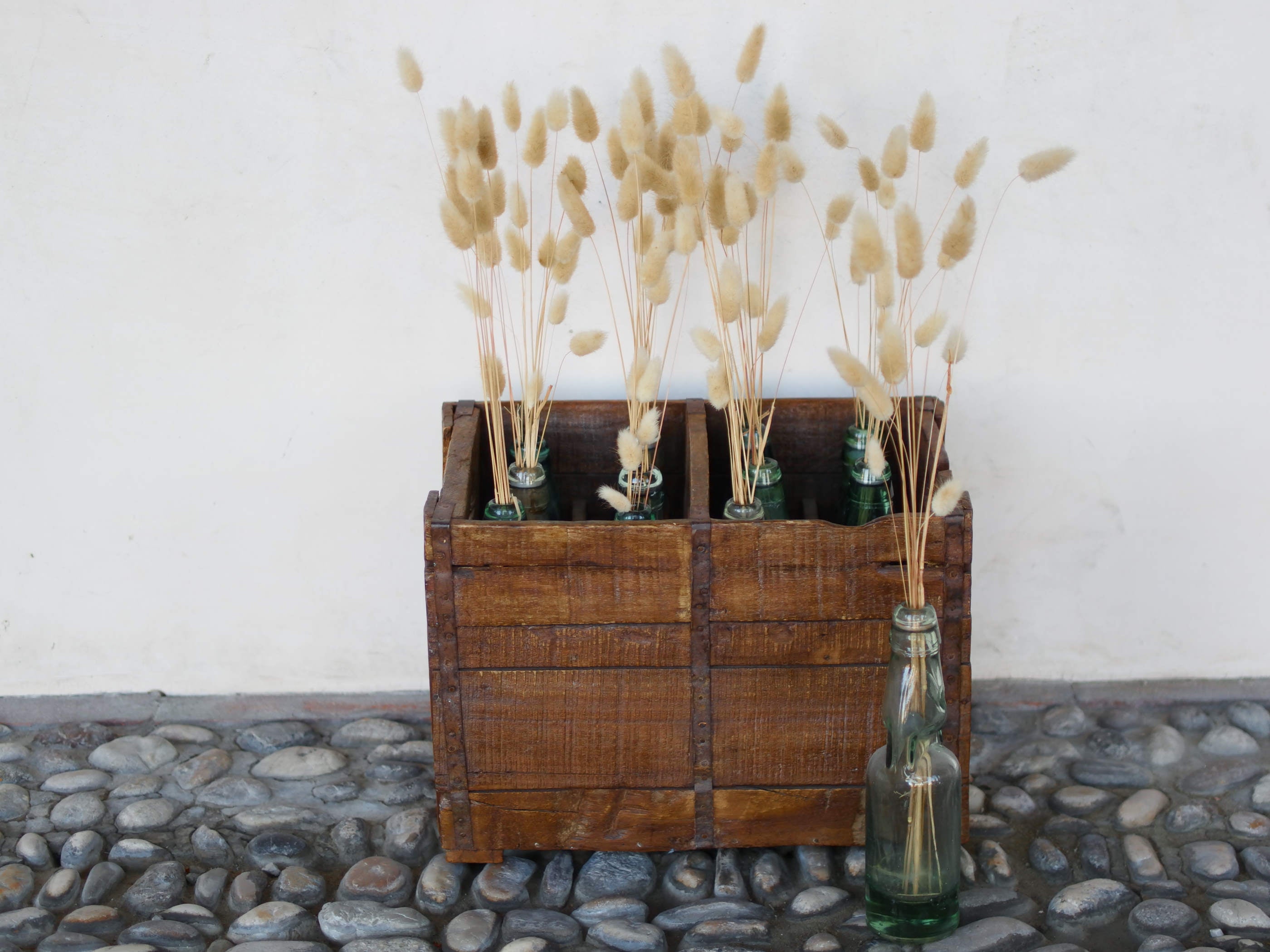Cassa in legno con 12 bottiglie per acqua frizzante. In uso in India dagli anni 40 ai primi anni 90 le bottiglie venovano usate per fare l'acqua frizzante. Bottiglie e cassetta interamente lavorate in modo artigianale, pezzo vintage originale e di difficile reperibilità se completo come l'articolo in foto. Ogni bottiglia è differente l'una dall'altra ed ogni cassa ha delle caratteristiche relative a fornitore, regione...  dimensioni 30x30xh40cm