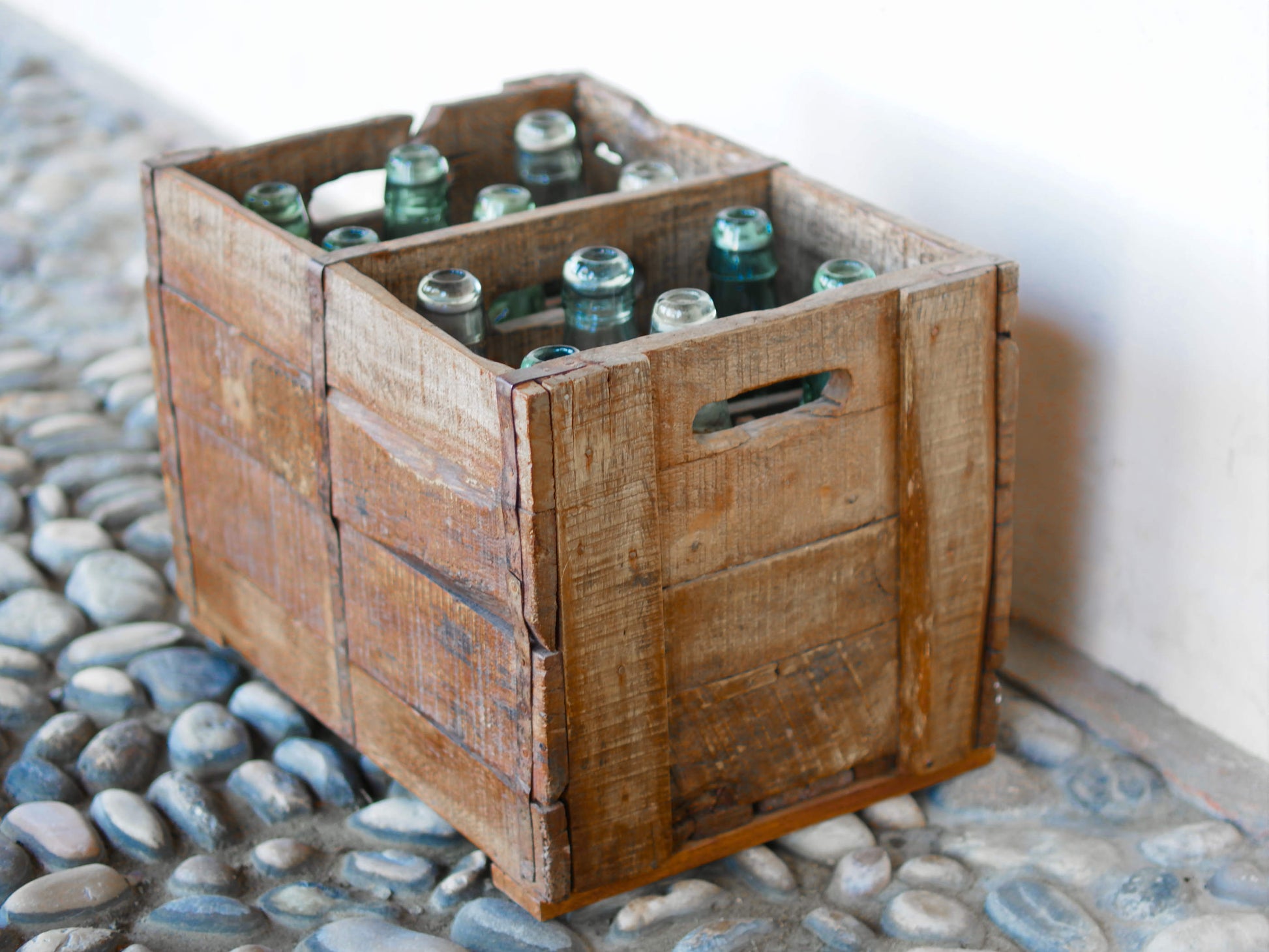 Cassa in legno con 12 bottiglie per acqua frizzante. In uso in India dagli anni 40 ai primi anni 90 le bottiglie venovano usate per fare l'acqua frizzante. Bottiglie e cassetta interamente lavorate in modo artigianale, pezzo vintage originale e di difficile reperibilità se completo come l'articolo in foto. Ogni bottiglia è differente l'una dall'altra ed ogni cassa ha delle caratteristiche relative a fornitore, regione...  dimensioni 30x30xh40cm