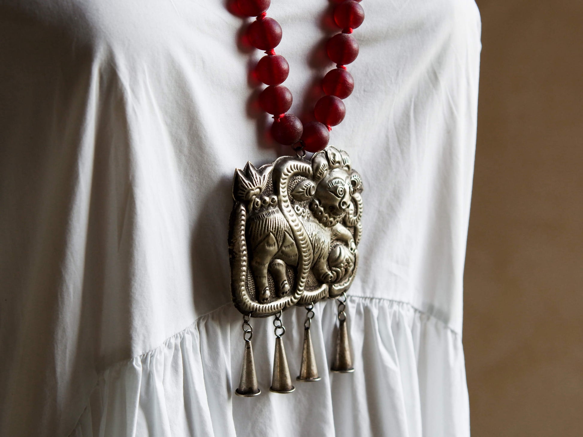 collana indiana in tessuto, pasta vitrea e lega di argento fatta a mano, sfere in pasta vitrea e nodini in cotone pendaglio con figura mitologica della cultura tibetana buddista lavorato in lega di argento  lunghezza totale ( circonferenza ) 80 cm pendaglio 9 x 7 cm escluse campane campanelle 3 cm peso 230 gr
