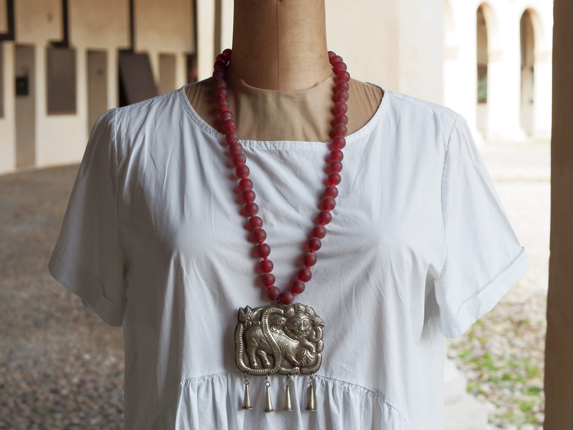 collana indiana in tessuto, pasta vitrea e lega di argento fatta a mano, sfere in pasta vitrea e nodini in cotone pendaglio con figura mitologica della cultura tibetana buddista lavorato in lega di argento  lunghezza totale ( circonferenza ) 80 cm pendaglio 9 x 7 cm escluse campane campanelle 3 cm peso 230 gr