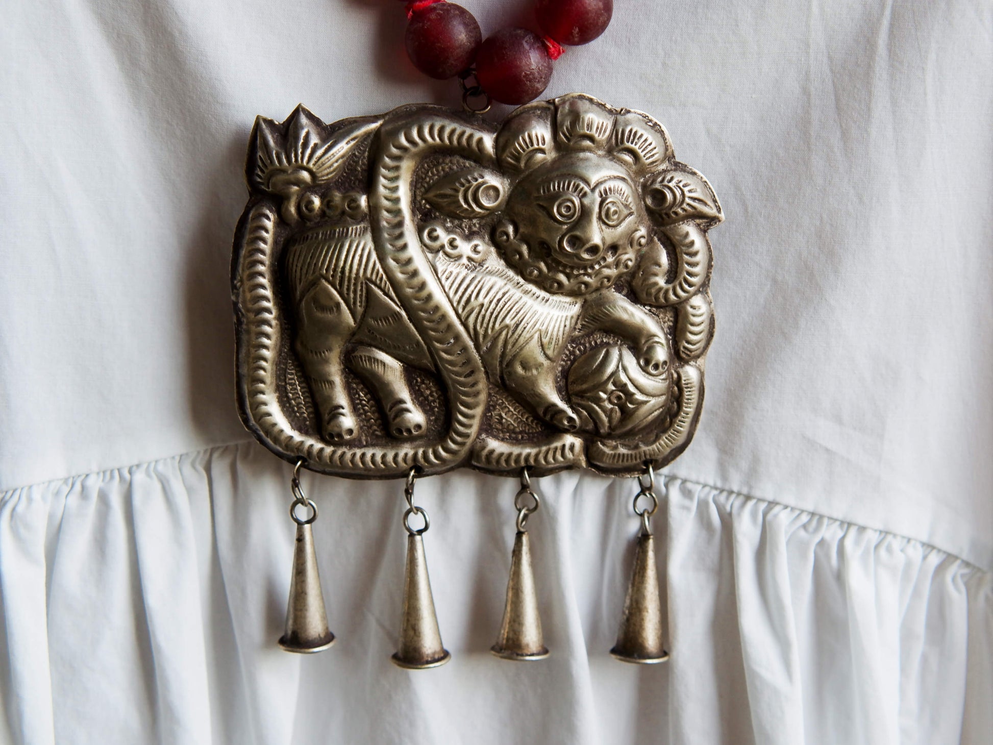 collana indiana in tessuto, pasta vitrea e lega di argento fatta a mano, sfere in pasta vitrea e nodini in cotone pendaglio con figura mitologica della cultura tibetana buddista lavorato in lega di argento  lunghezza totale ( circonferenza ) 80 cm pendaglio 9 x 7 cm escluse campane campanelle 3 cm peso 230 gr