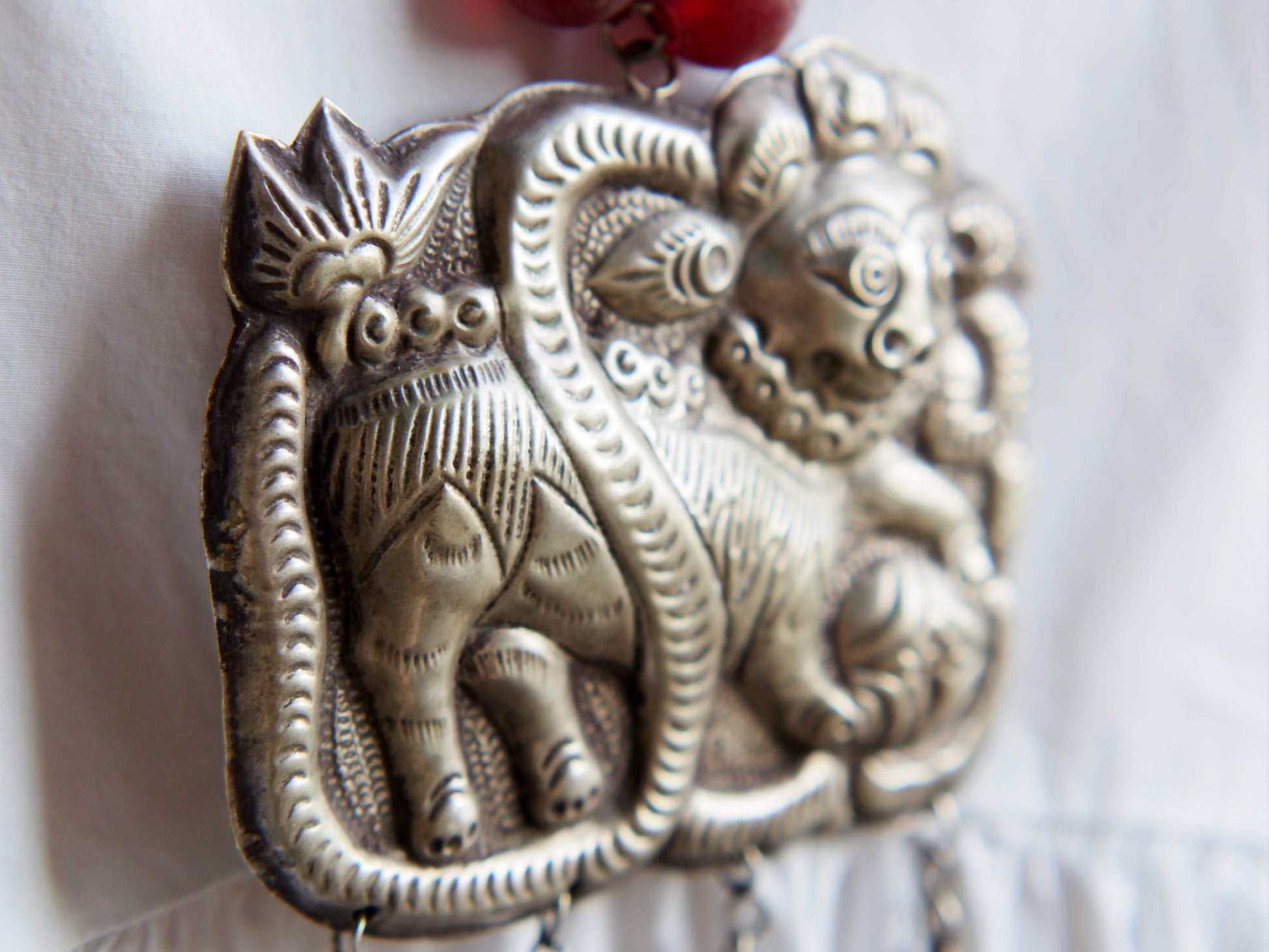 collana indiana in tessuto, pasta vitrea e lega di argento fatta a mano, sfere in pasta vitrea e nodini in cotone pendaglio con figura mitologica della cultura tibetana buddista lavorato in lega di argento  lunghezza totale ( circonferenza ) 80 cm pendaglio 9 x 7 cm escluse campane campanelle 3 cm peso 230 gr