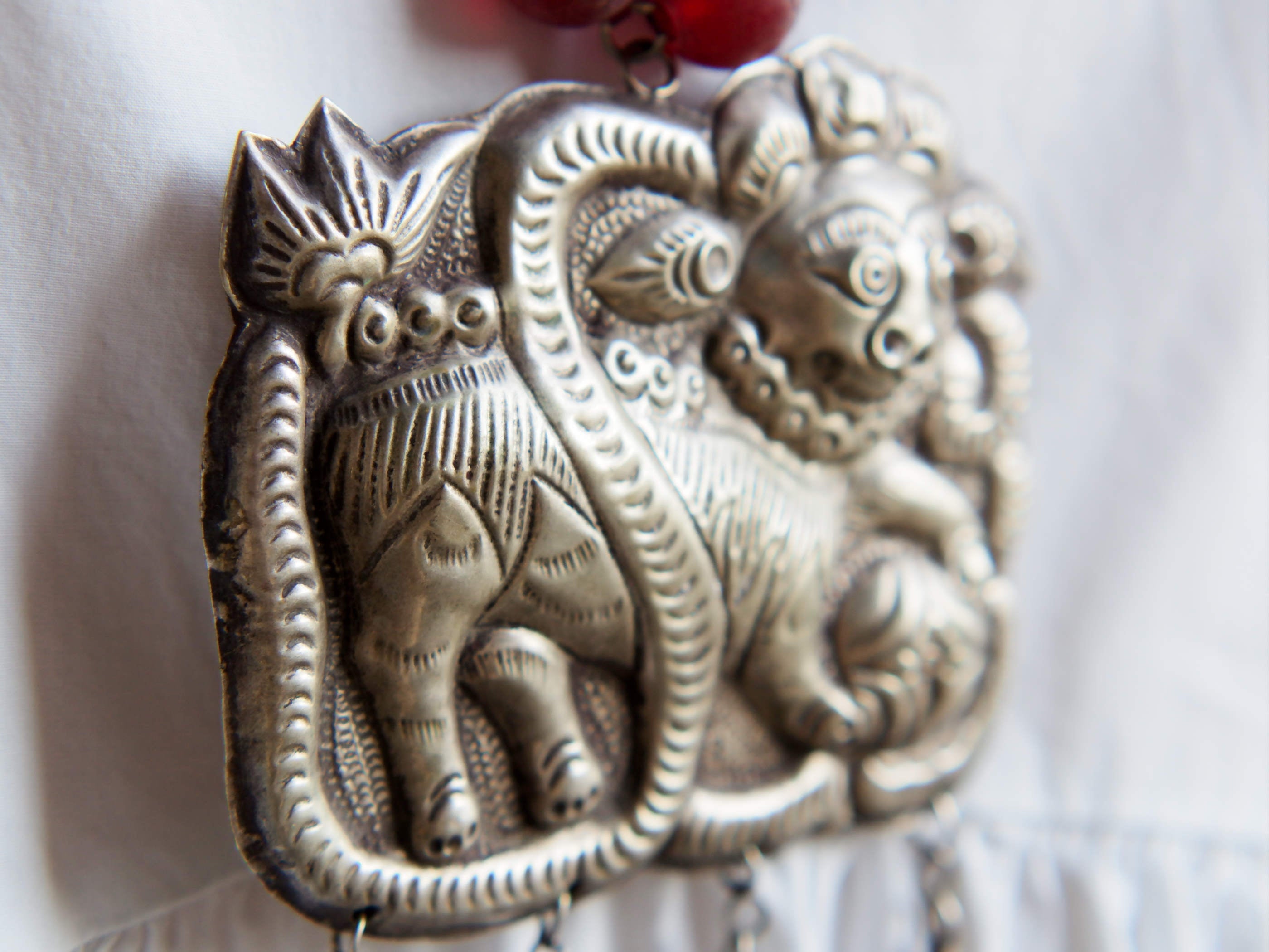 collana indiana in tessuto, pasta vitrea e lega di argento fatta a mano, sfere in pasta vitrea e nodini in cotone pendaglio con figura mitologica della cultura tibetana buddista lavorato in lega di argento  lunghezza totale ( circonferenza ) 80 cm pendaglio 9 x 7 cm escluse campane campanelle 3 cm peso 230 gr