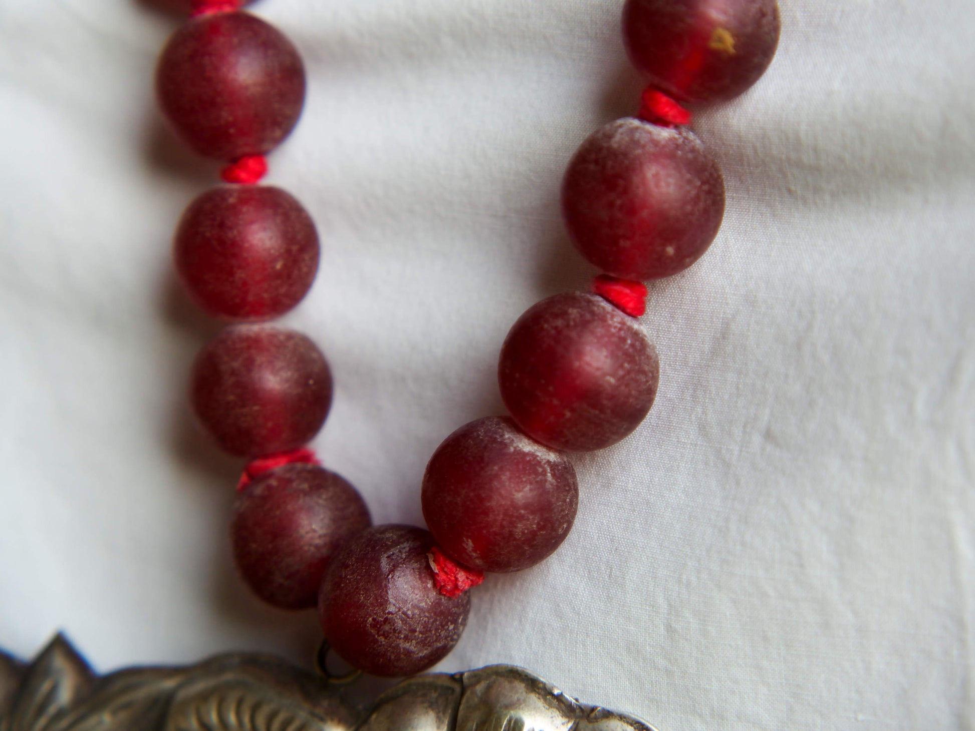 collana indiana in tessuto, pasta vitrea e lega di argento fatta a mano, sfere in pasta vitrea e nodini in cotone pendaglio con figura mitologica della cultura tibetana buddista lavorato in lega di argento  lunghezza totale ( circonferenza ) 80 cm pendaglio 9 x 7 cm escluse campane campanelle 3 cm peso 230 gr