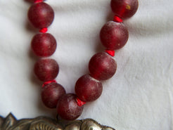 collana indiana in tessuto, pasta vitrea e lega di argento fatta a mano, sfere in pasta vitrea e nodini in cotone pendaglio con figura mitologica della cultura tibetana buddista lavorato in lega di argento  lunghezza totale ( circonferenza ) 80 cm pendaglio 9 x 7 cm escluse campane campanelle 3 cm peso 230 gr