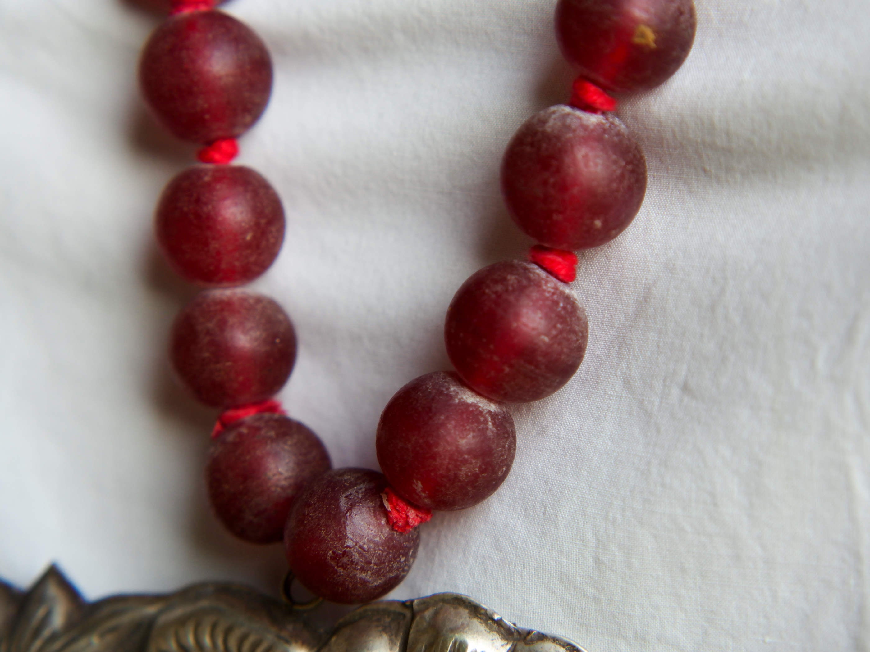 collana indiana in tessuto, pasta vitrea e lega di argento fatta a mano, sfere in pasta vitrea e nodini in cotone pendaglio con figura mitologica della cultura tibetana buddista lavorato in lega di argento  lunghezza totale ( circonferenza ) 80 cm pendaglio 9 x 7 cm escluse campane campanelle 3 cm peso 230 gr