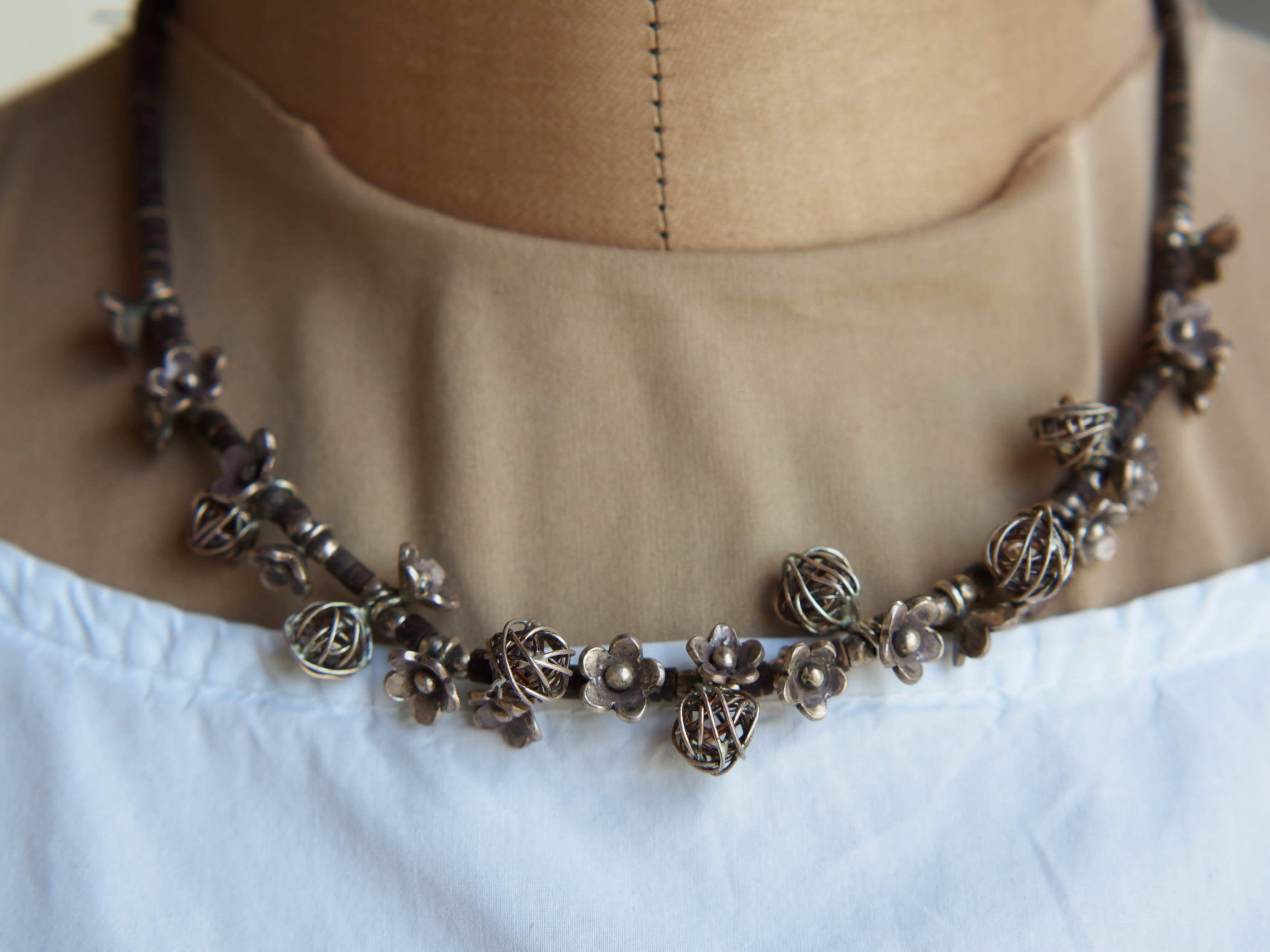 Primo piano della collana girocollo etnica indiana in argento e cocco, con micro elementi e fiori lavorati a mano.