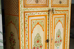 Dettaglio ravvicinato degli archi Mughal dipinti a mano che incorniciano i pannelli dell'armadio coloniale.