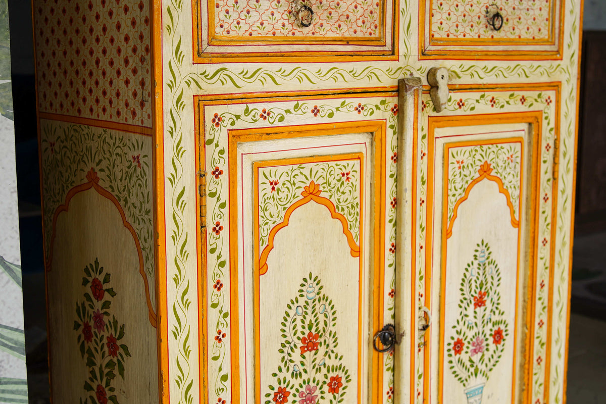 Dettaglio ravvicinato degli archi Mughal dipinti a mano che incorniciano i pannelli dell'armadio coloniale.