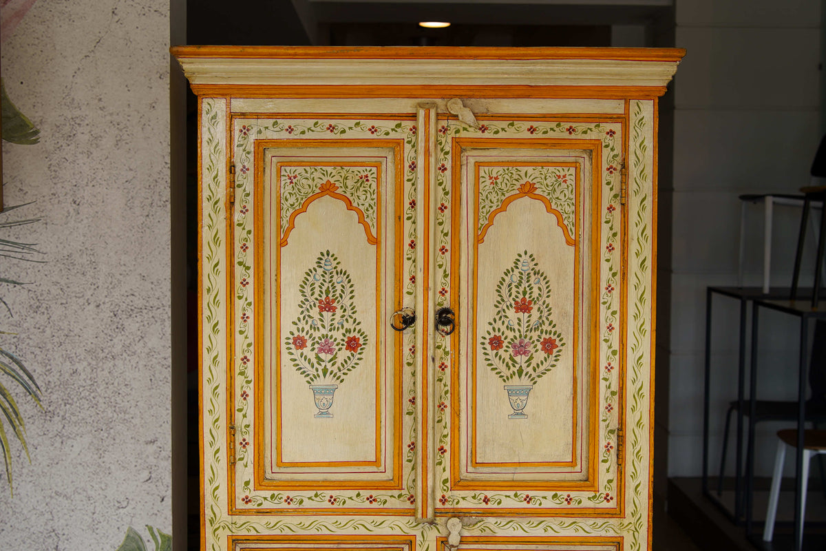 Dettaglio delle ante intagliate con motivi floreali a candelabra e finitura avorio su credenza coloniale in teak