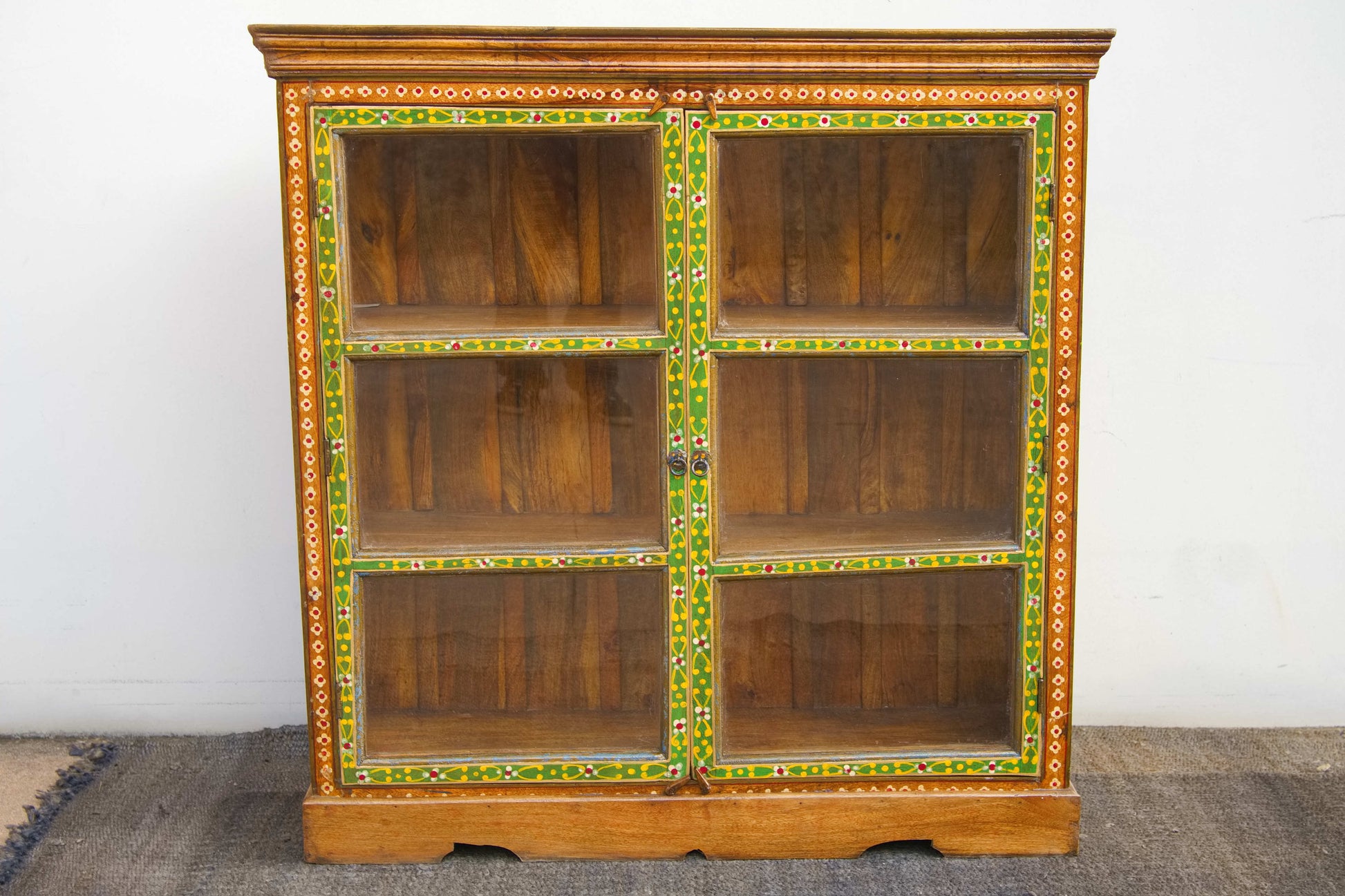 Vista d'insieme della credenza indiana coloniale in teak dipinto con ante a vetro.