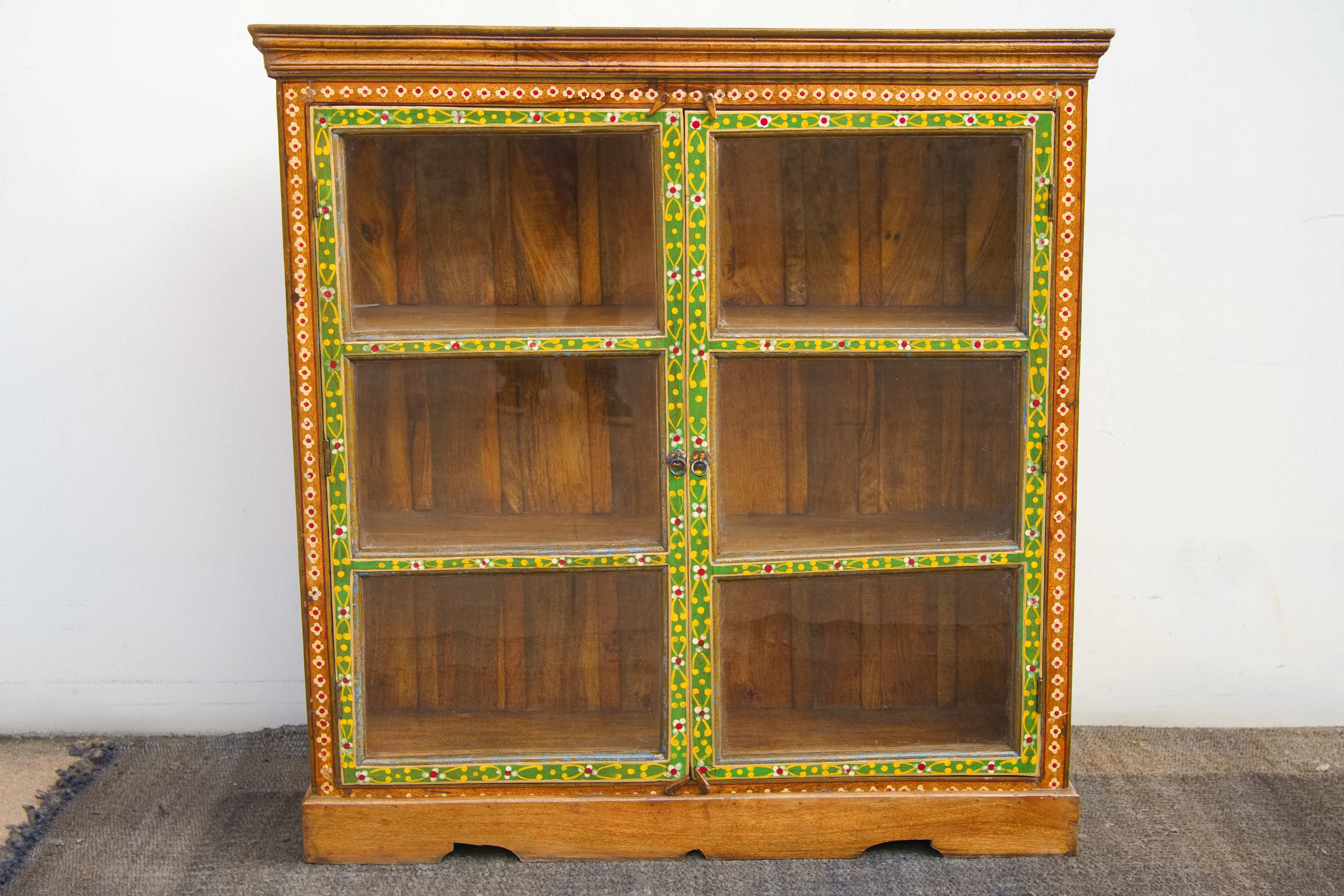 Vista d'insieme della credenza indiana coloniale in teak dipinto con ante a vetro.