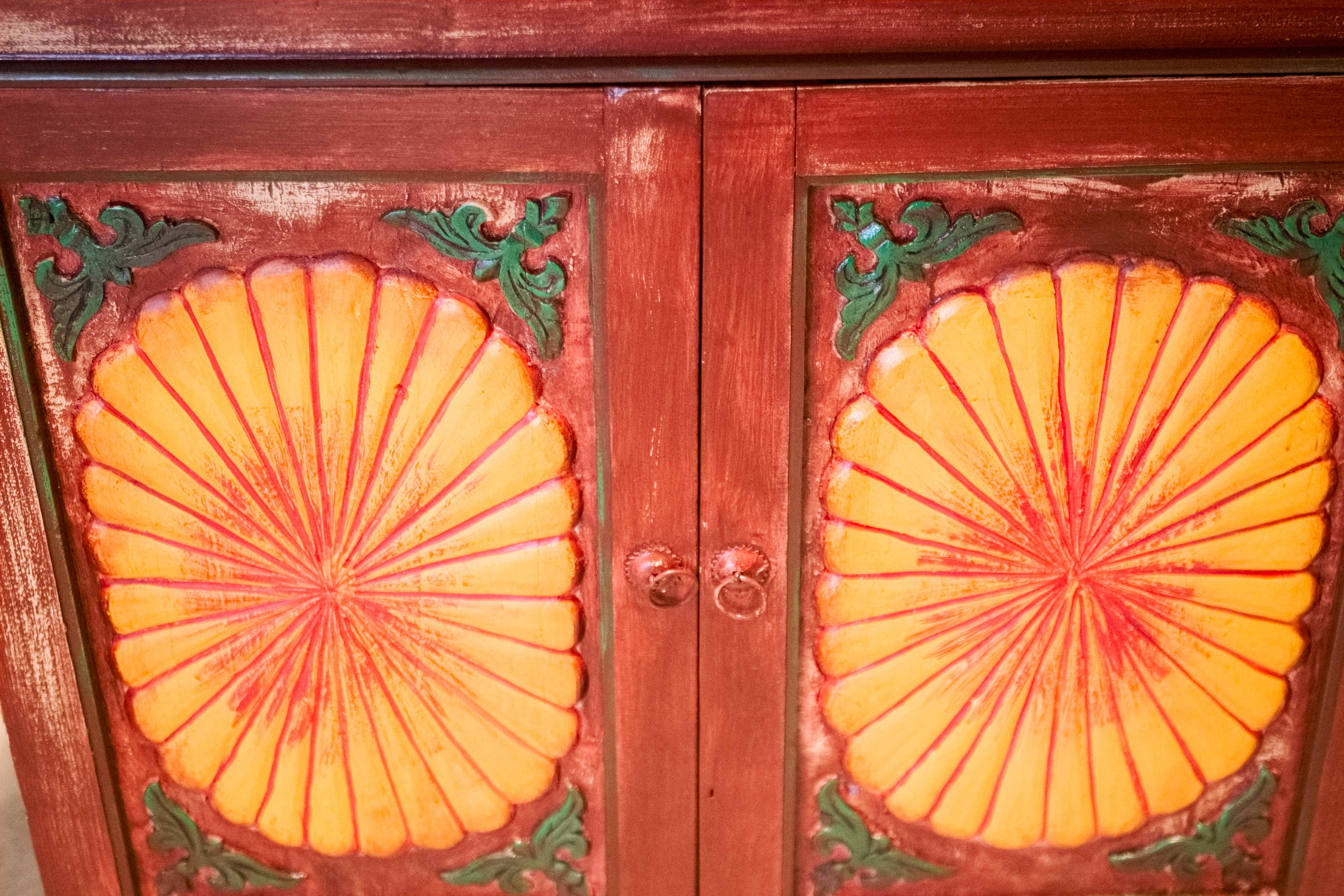 Primo piano dei dettagli decorativi a rilievo in pasta di gesso agli angoli delle ante dell'armadietto indiano.