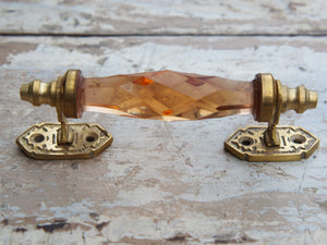 Maniglia in vetro lievemente sfaccettato di colore ambra su supporto in metallo color oro. Disponibile in altri colori come da foto.  dimensioni 14x5x3cm