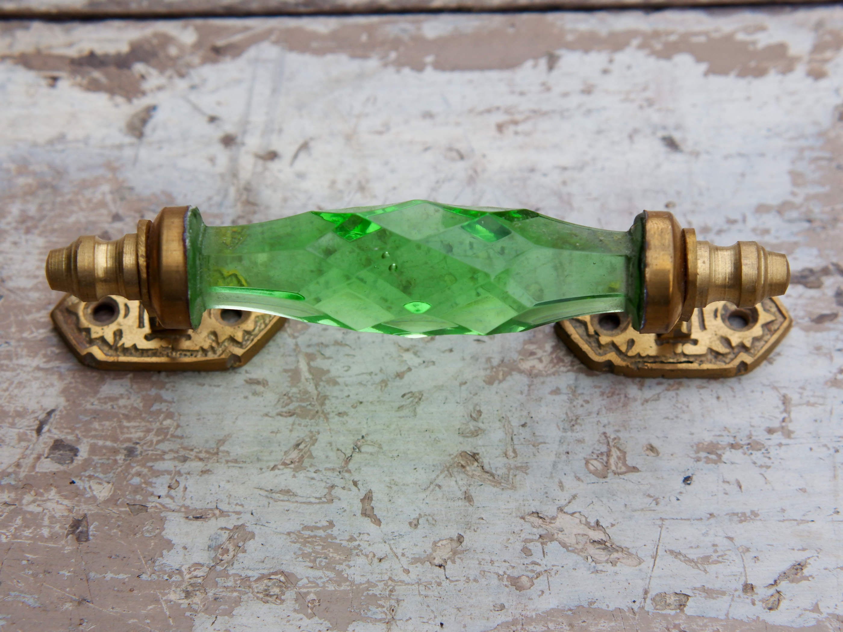 Maniglia in vetro lievemente sfaccettato di colore verde su supporto in metallo color oro. Disponibile in altri colori come da foto.  dimensioni 14x5x3cm