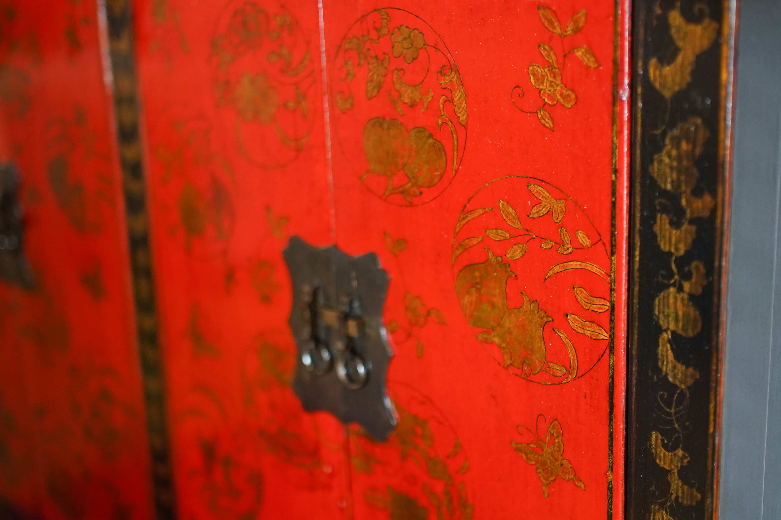 Dettaglio della pregiata laccatura rossa e nera con disegni in oro su credenza cinese antica dei primi del Novecento.