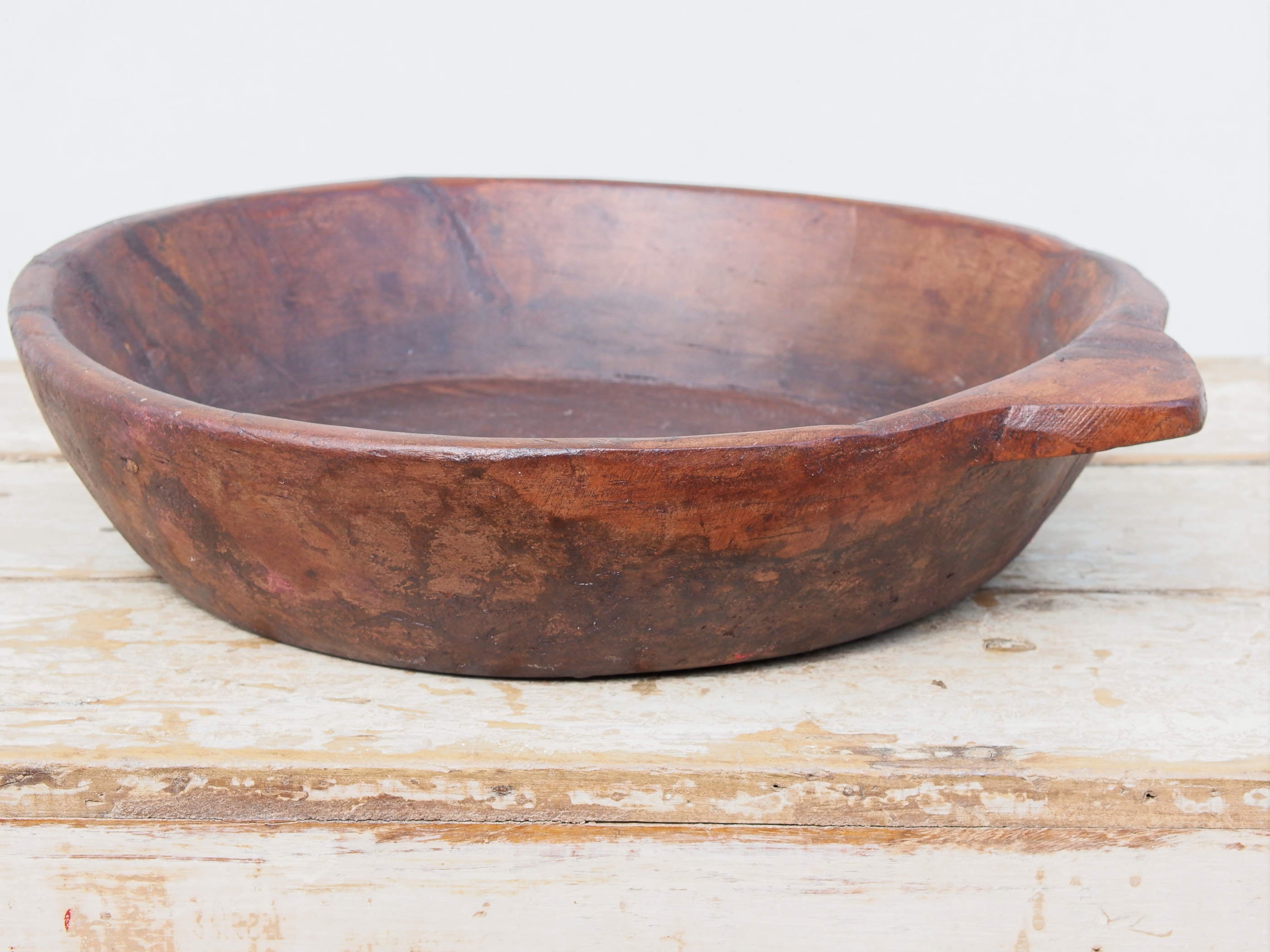 piatto in legno ricavato da un unico tronco di legno. usato in principio come piatto, setaccio per esiccare i cereali. tronco unico di teak massello databile inizio / metà 900.  dimensioni 42x47 h 10cm.