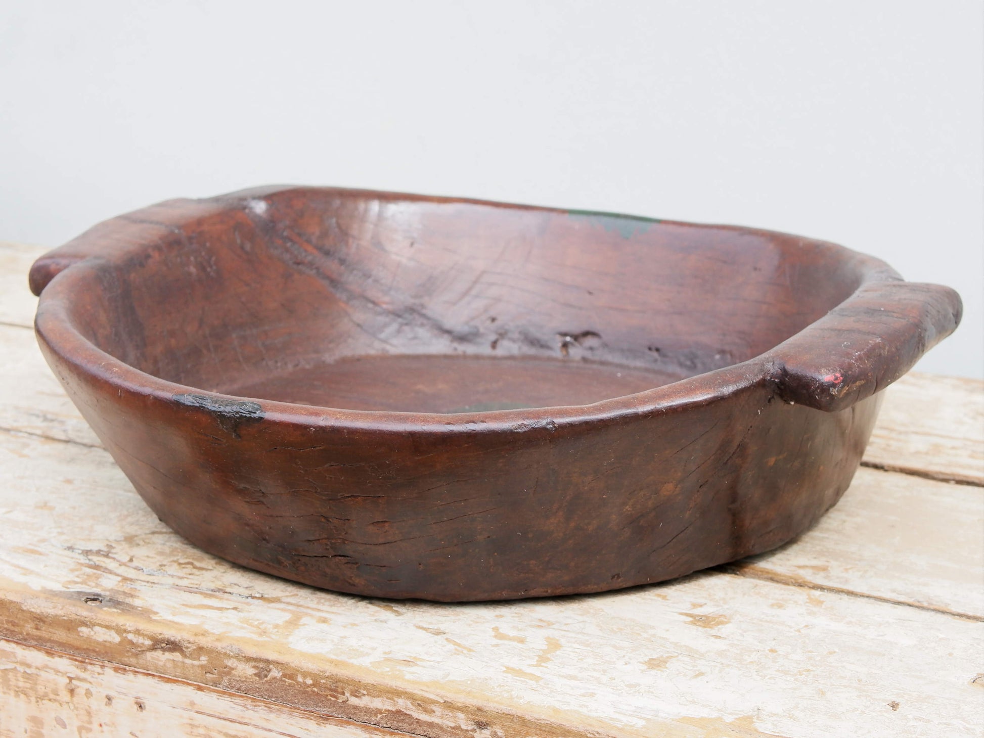 piatto in legno con manico ricavato da un unico tronco di legno con manici. usato in principio come piatto , setaccio per esiccare i cereali tronco unico di teak massello databile inizio / metà 900  dimensioni 47x42 h11cm.