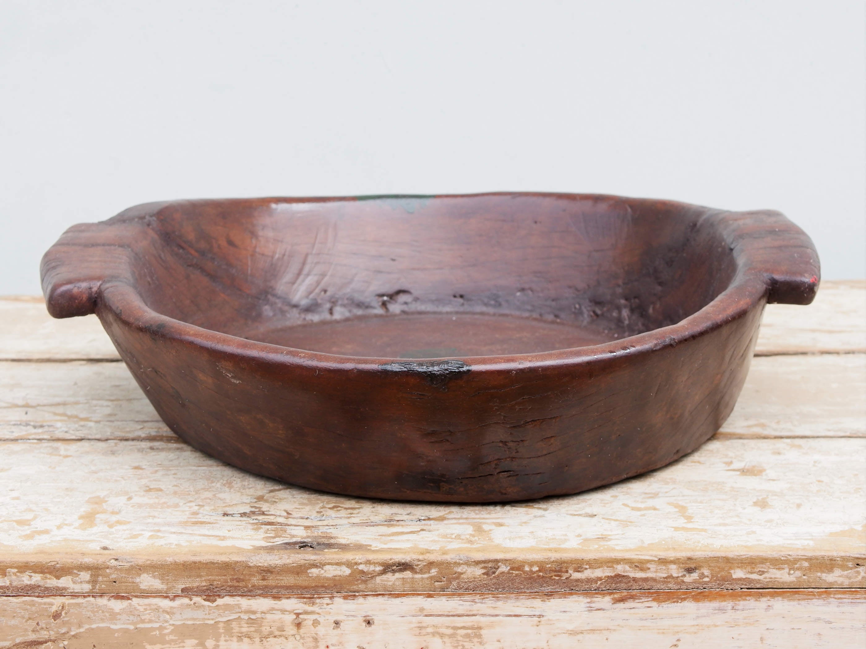 piatto in legno con manico ricavato da un unico tronco di legno con manici. usato in principio come piatto , setaccio per esiccare i cereali tronco unico di teak massello databile inizio / metà 900  dimensioni 47x42 h11cm.