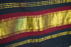 Particolare della fascia decorativa laterale con righe bordeaux e inserti metallici dorati.