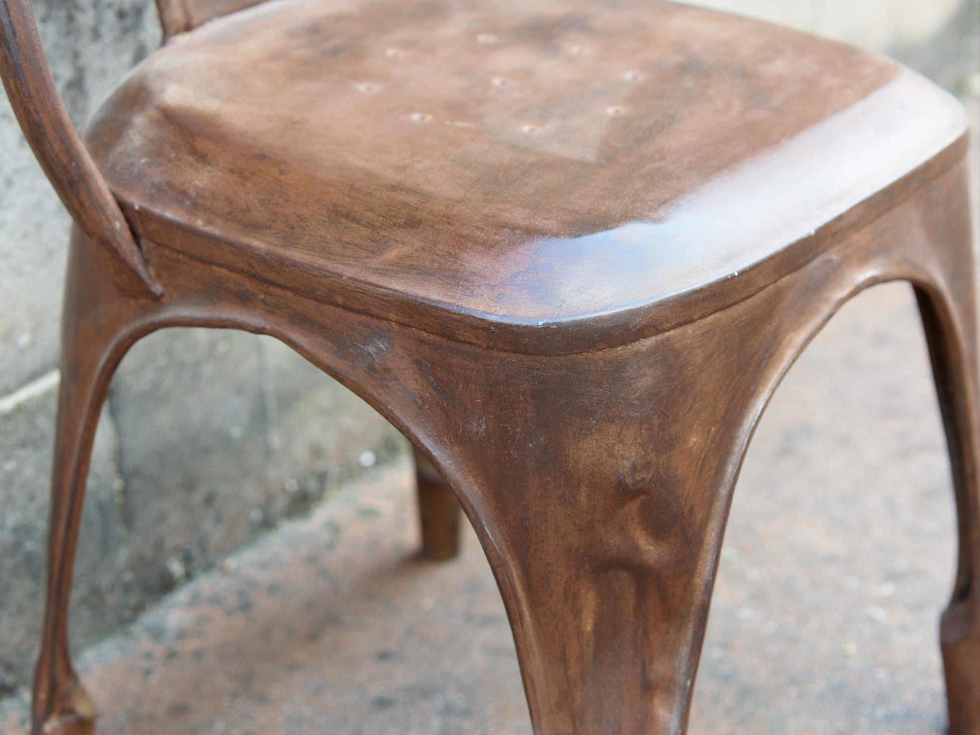 Primo piano della patina metallica e dei dettagli di usura controllata sulla superficie.