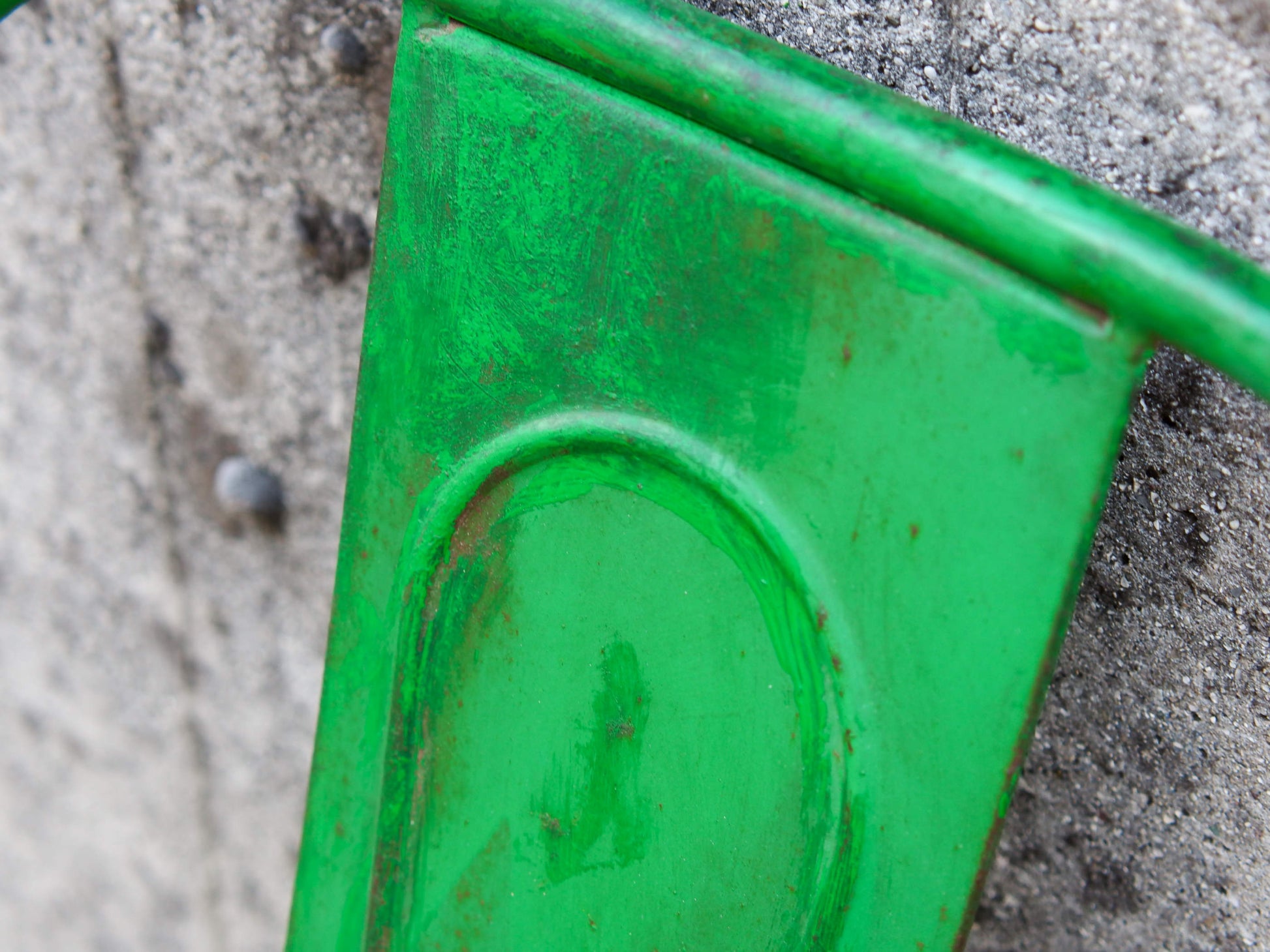 Dettaglio dei tubolari metallici ricurvi che compongono la struttura dello schienale verde.