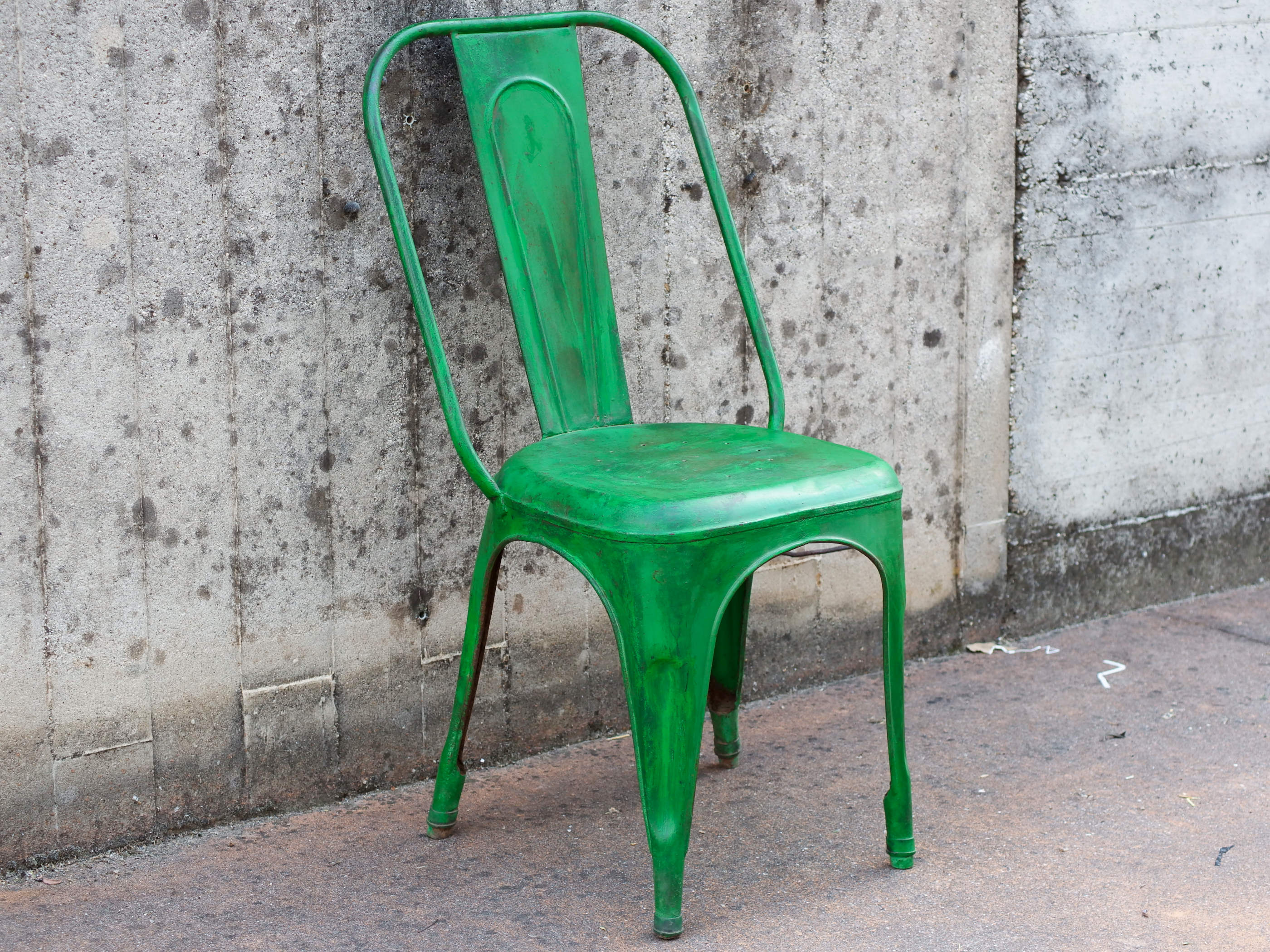 Angolazione prospettica della sedia vintage verde intesa come pezzo unico d'arredo.