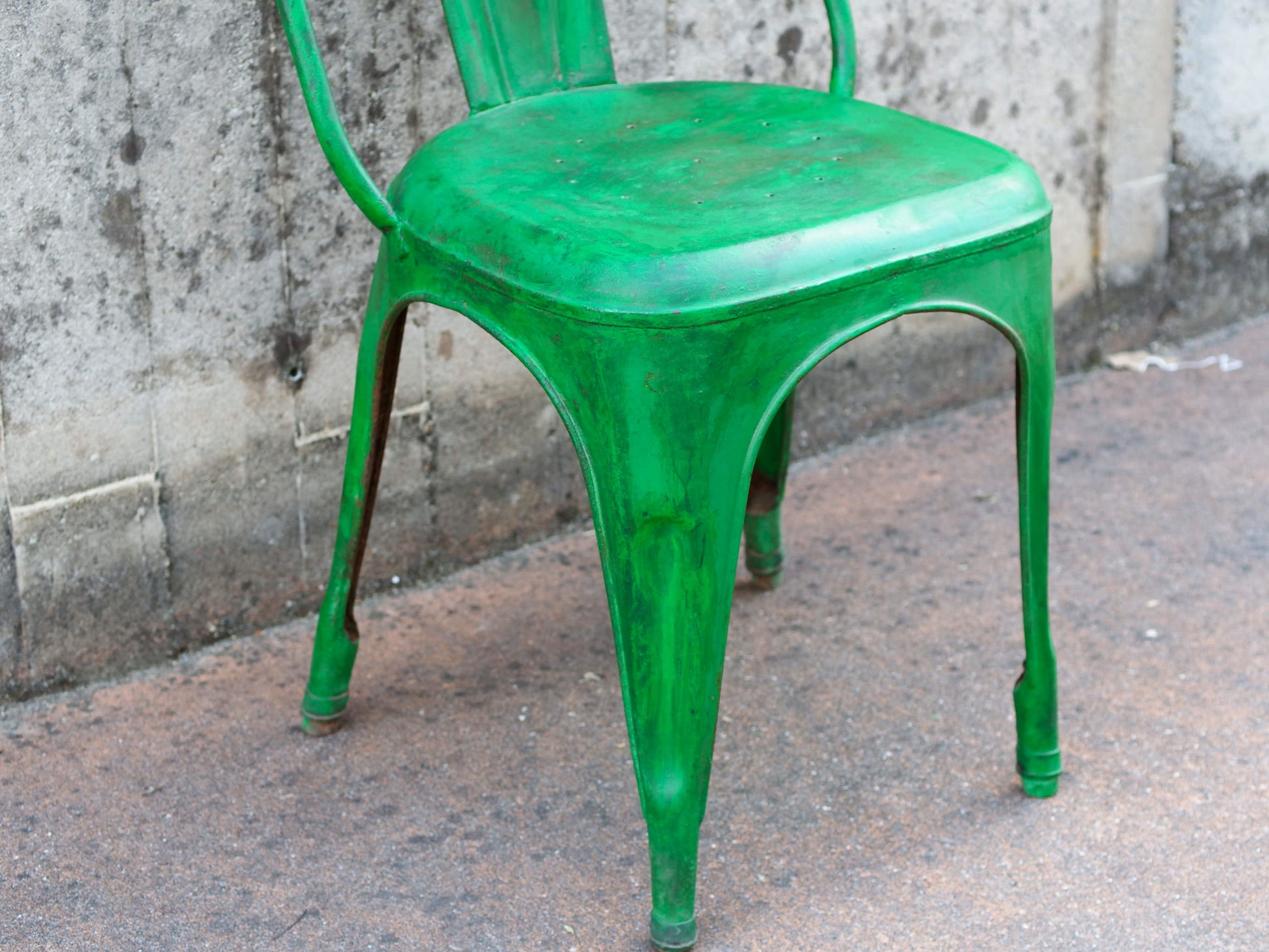 Particolare della seduta metallica verde con i segni caratteristici dell'usura artigianale.