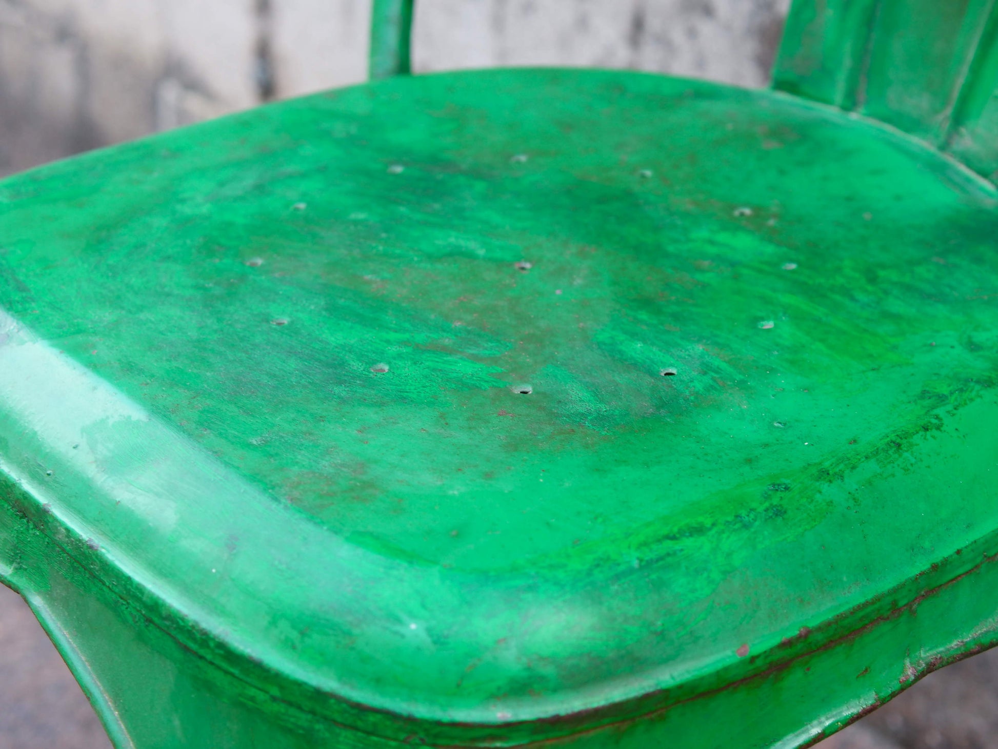 Particolare della seduta metallica verde con i segni caratteristici dell'usura artigianale.