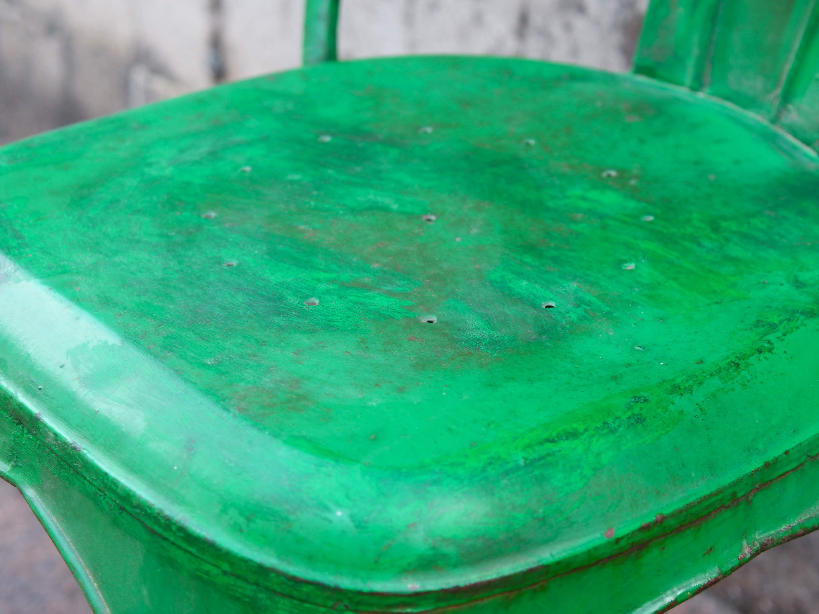 Particolare della seduta metallica verde con i segni caratteristici dell'usura artigianale.